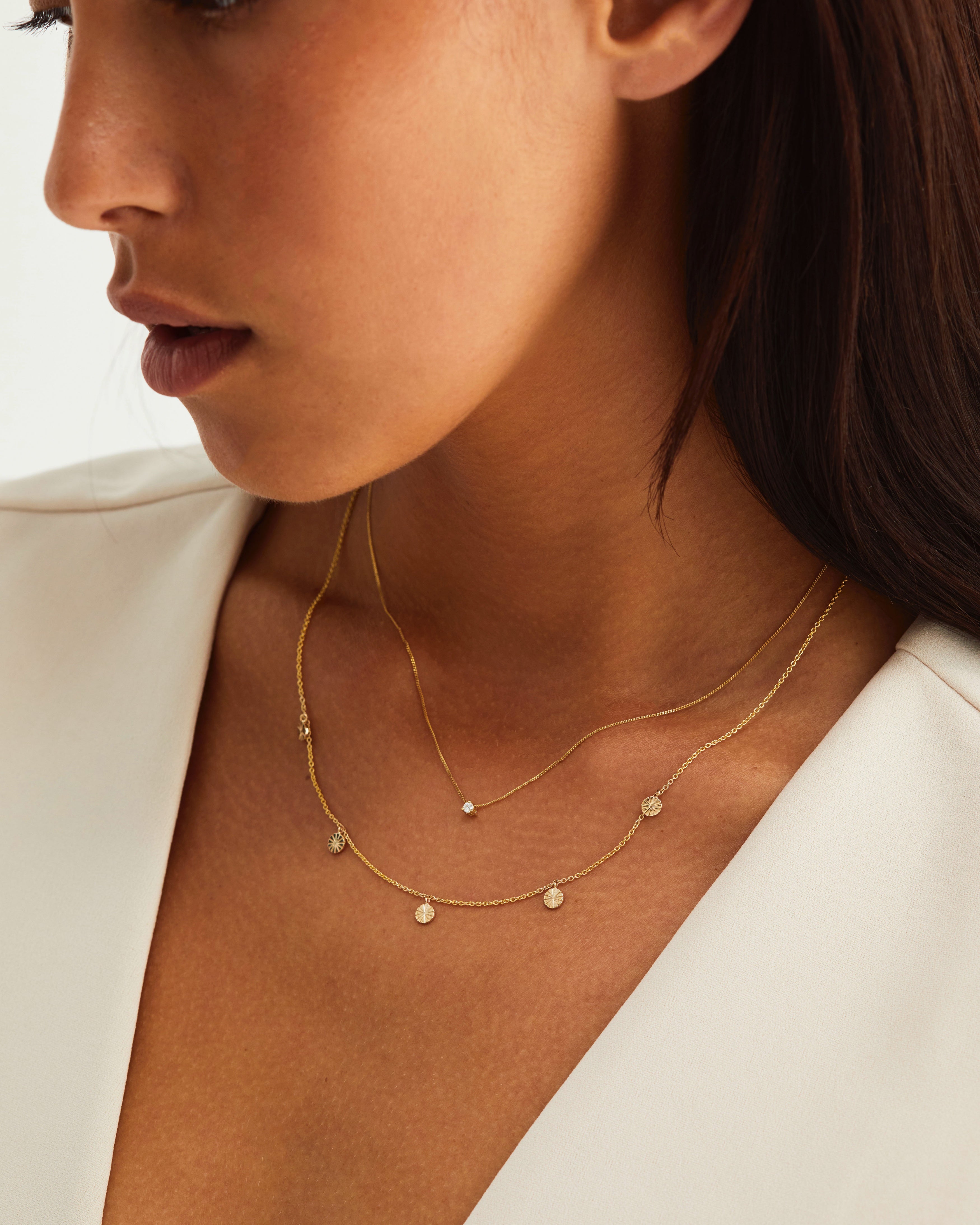 A woman wearing the Jia Charm Necklace in yellow gold.