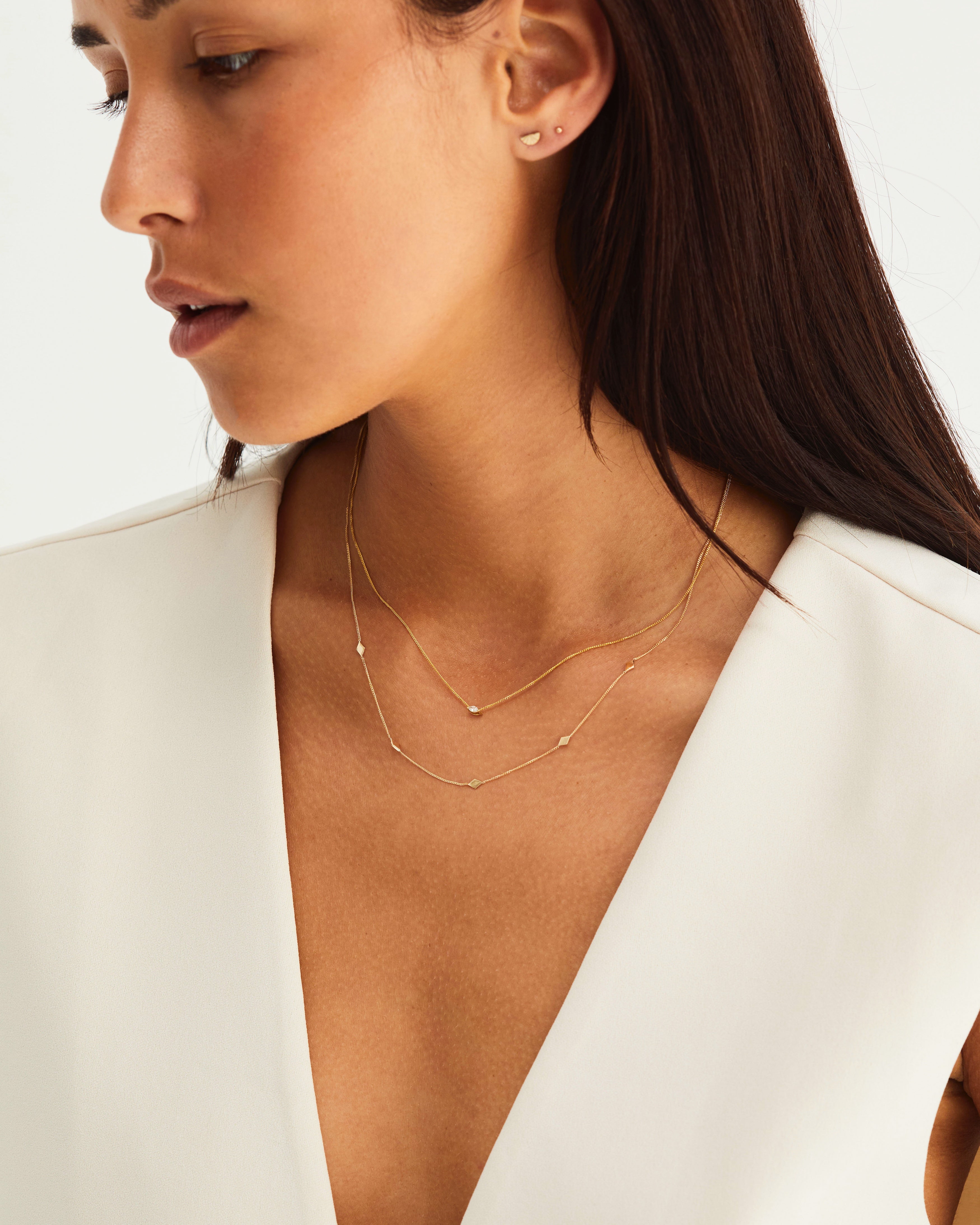 A woman waering the Nuna Charm Necklace in yellow gold.