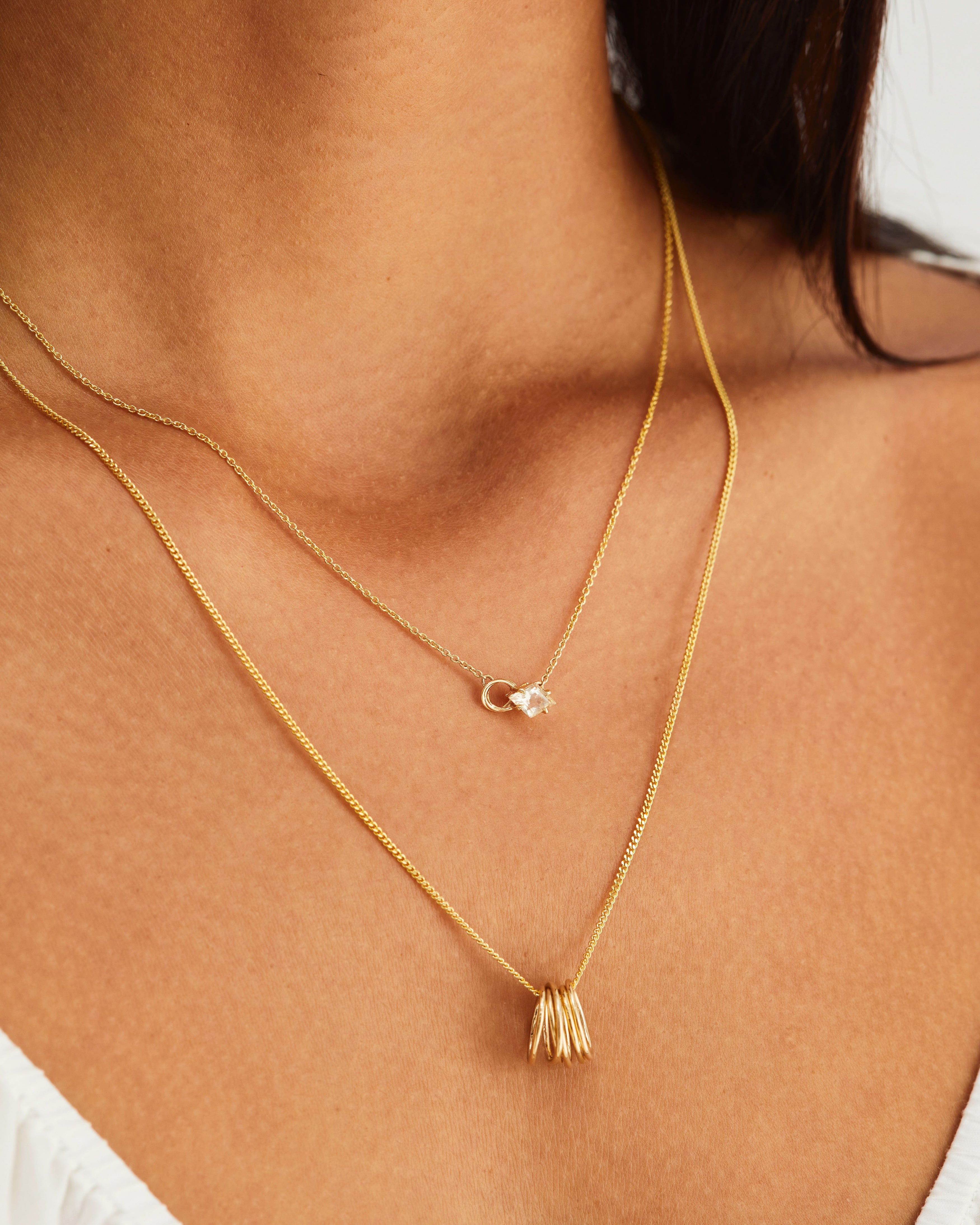 A woman wearing the Nuna Necklace | Savannah Sunstone and the Six Oval Necklace, both in yellow gold.