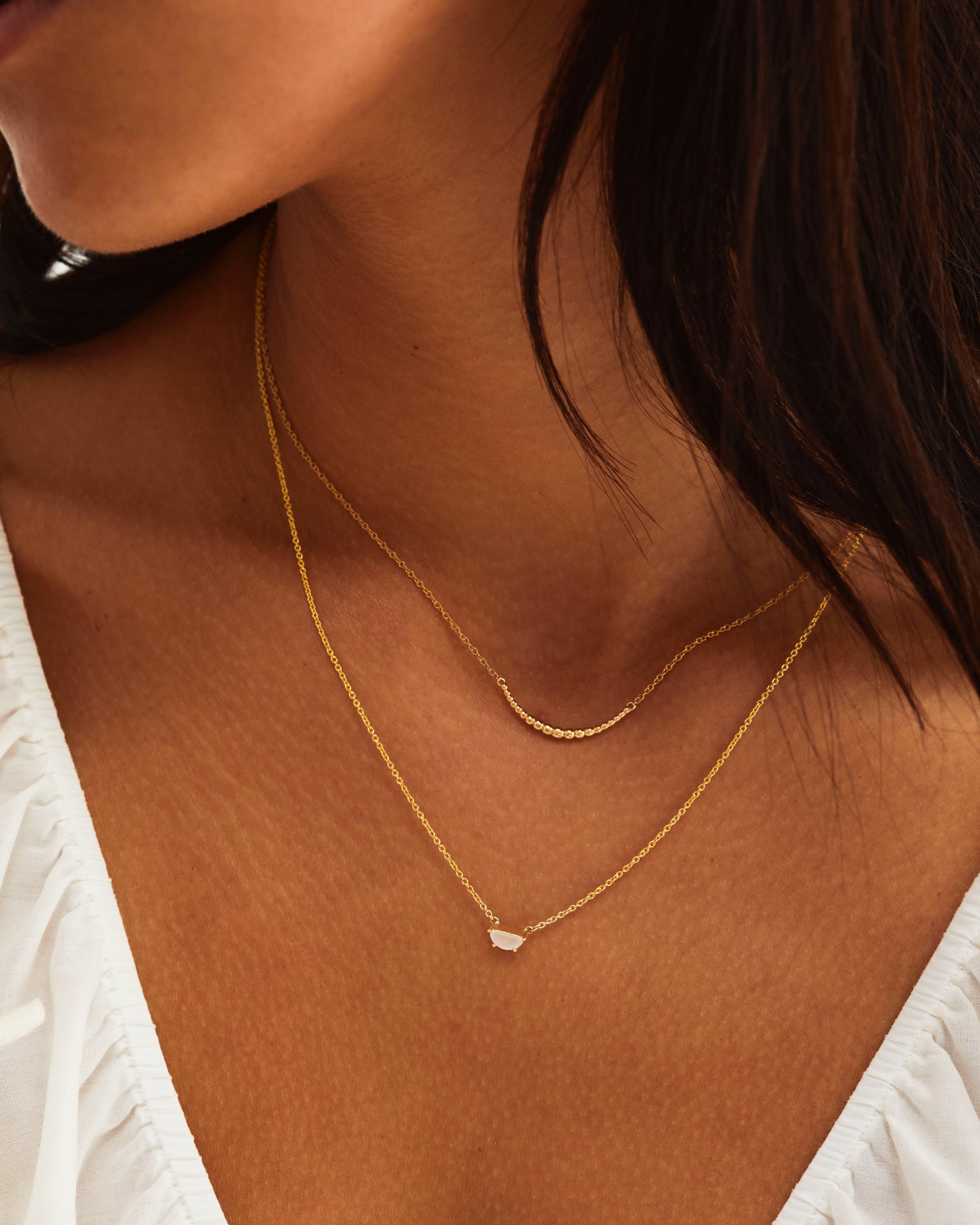A model wears our gold crescent necklace layered with a moonstone necklace