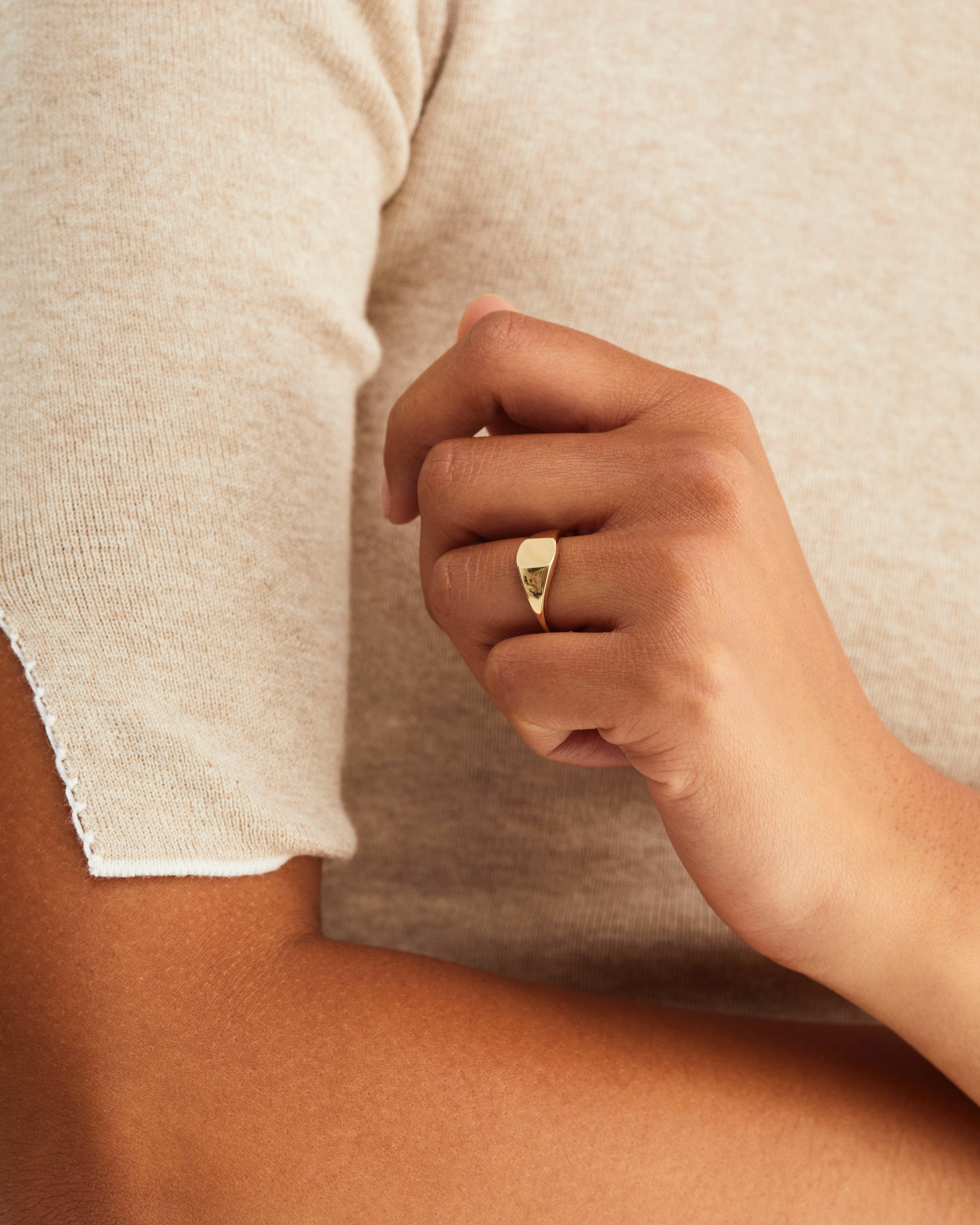 A woman wearing the fei signet in yellow gold