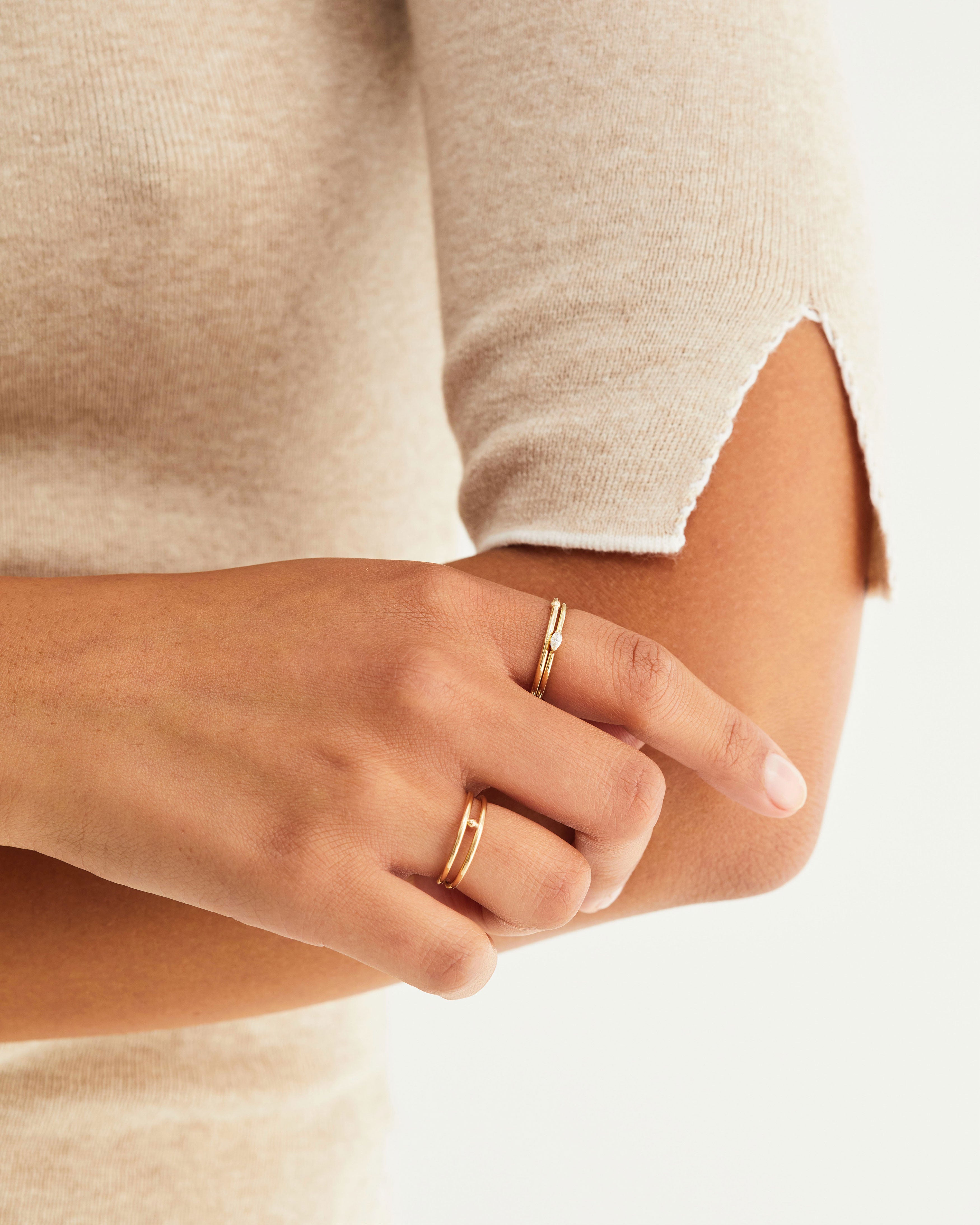 A woman wears a Vega stacking ring with the suspend ring and double reliquum ring, all in yellow gold.