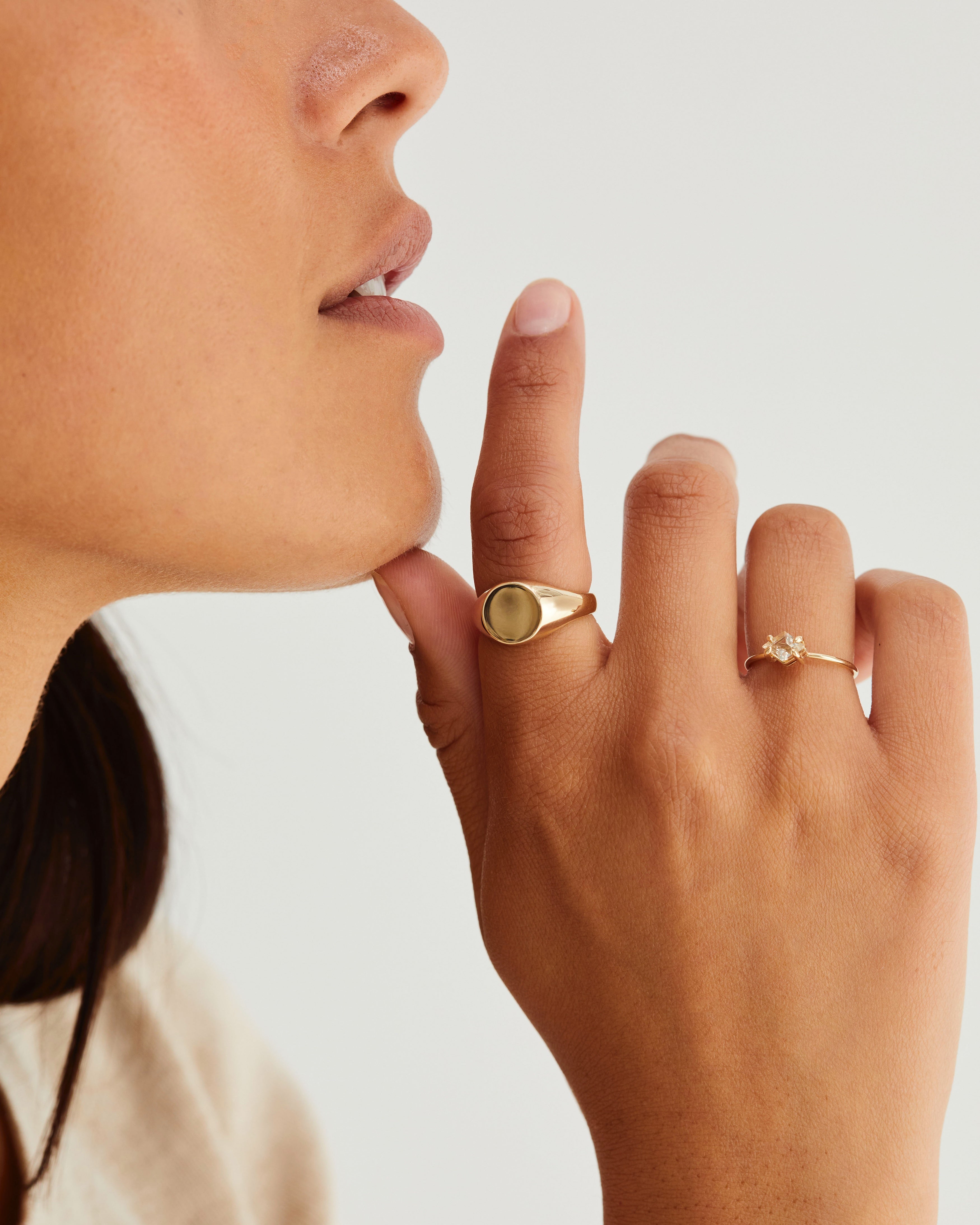 A woman wearing the Kian Signet Ring and the Mai Ring | Sunstone, both in yellow gold.