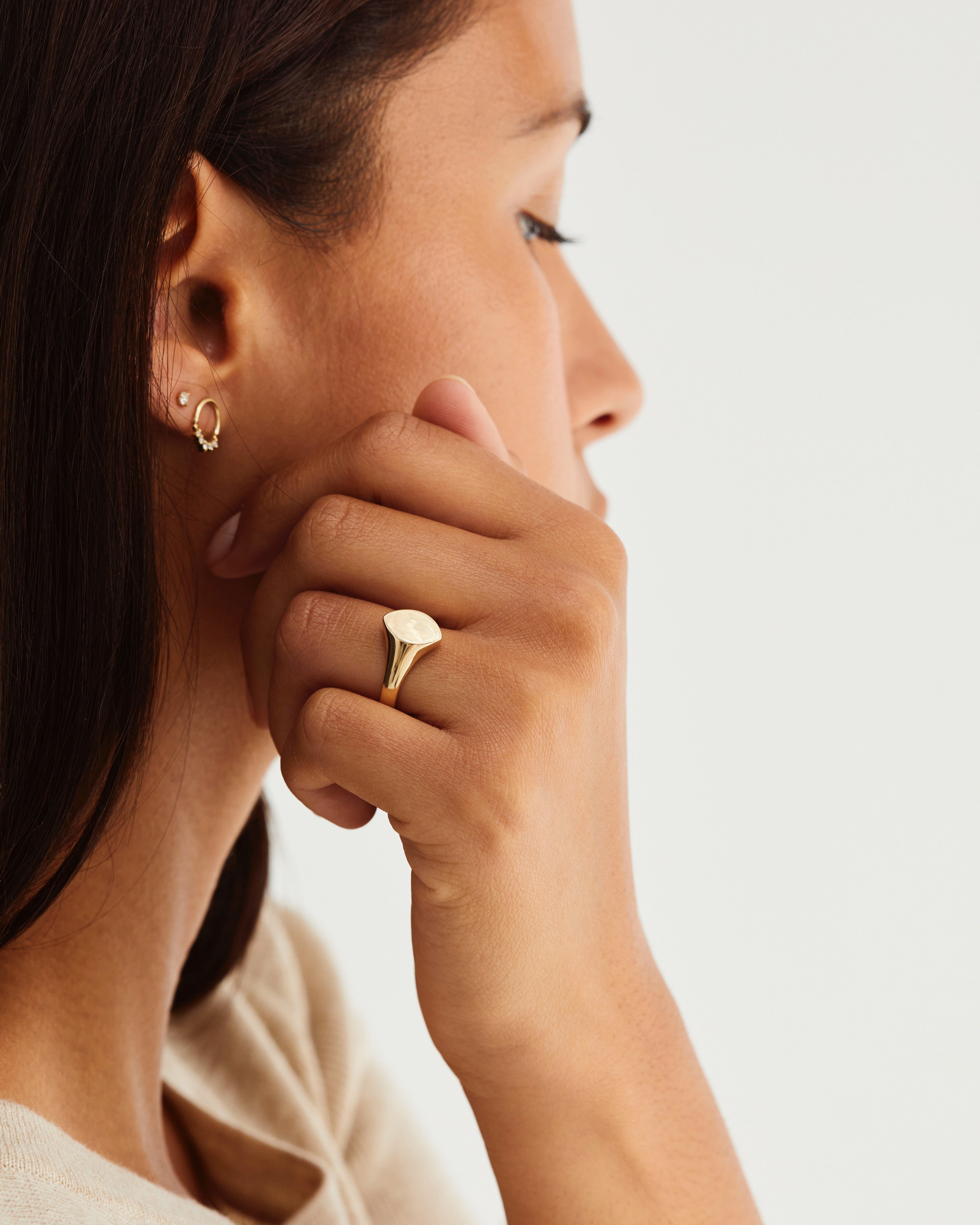 A woman's hand adorned with the Willow Signet Ring in yellow gold.