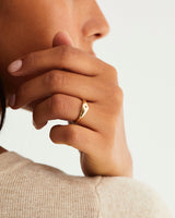 A woman wearing the Nuna Signet Ring in yellow gold, featuring an accent stone.
