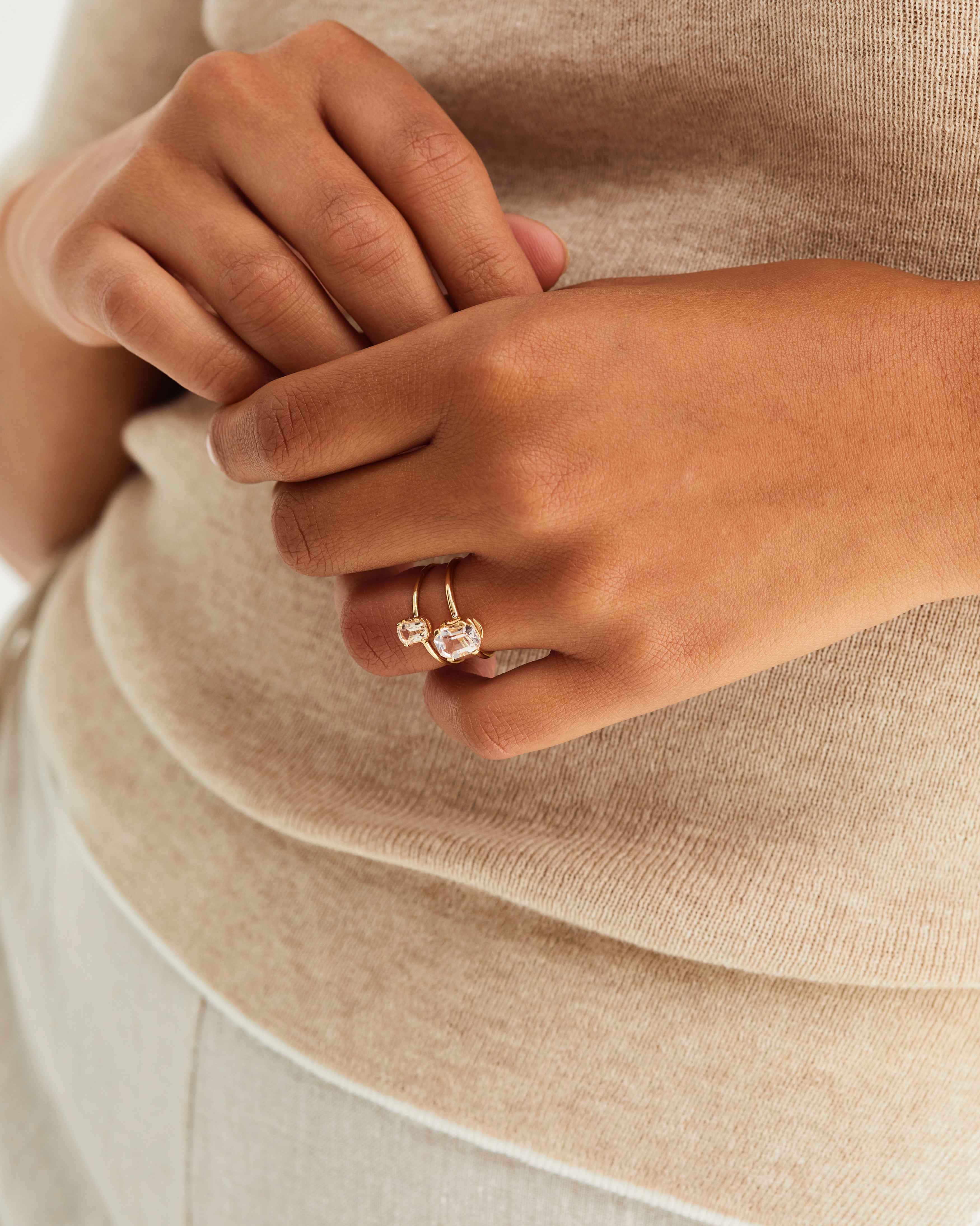 A woman's hands, showcasing the Fei Ring | Morganite and Tiny Fei Ring | Morganite, both in yellow gold.