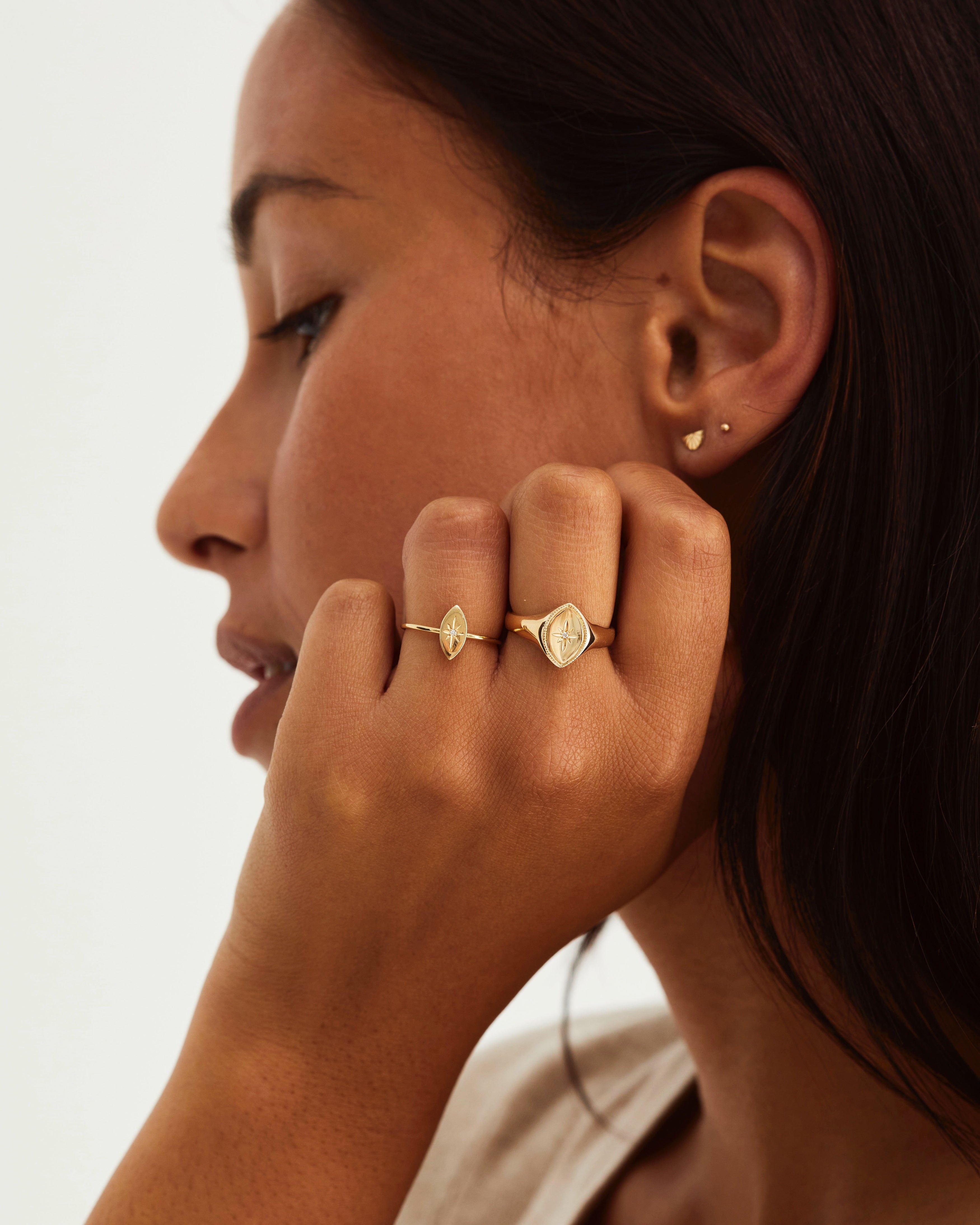 A woman wearing the Willow Signet with a white diamond set in the centre, as well as the Willow Ring, also with a white diamond