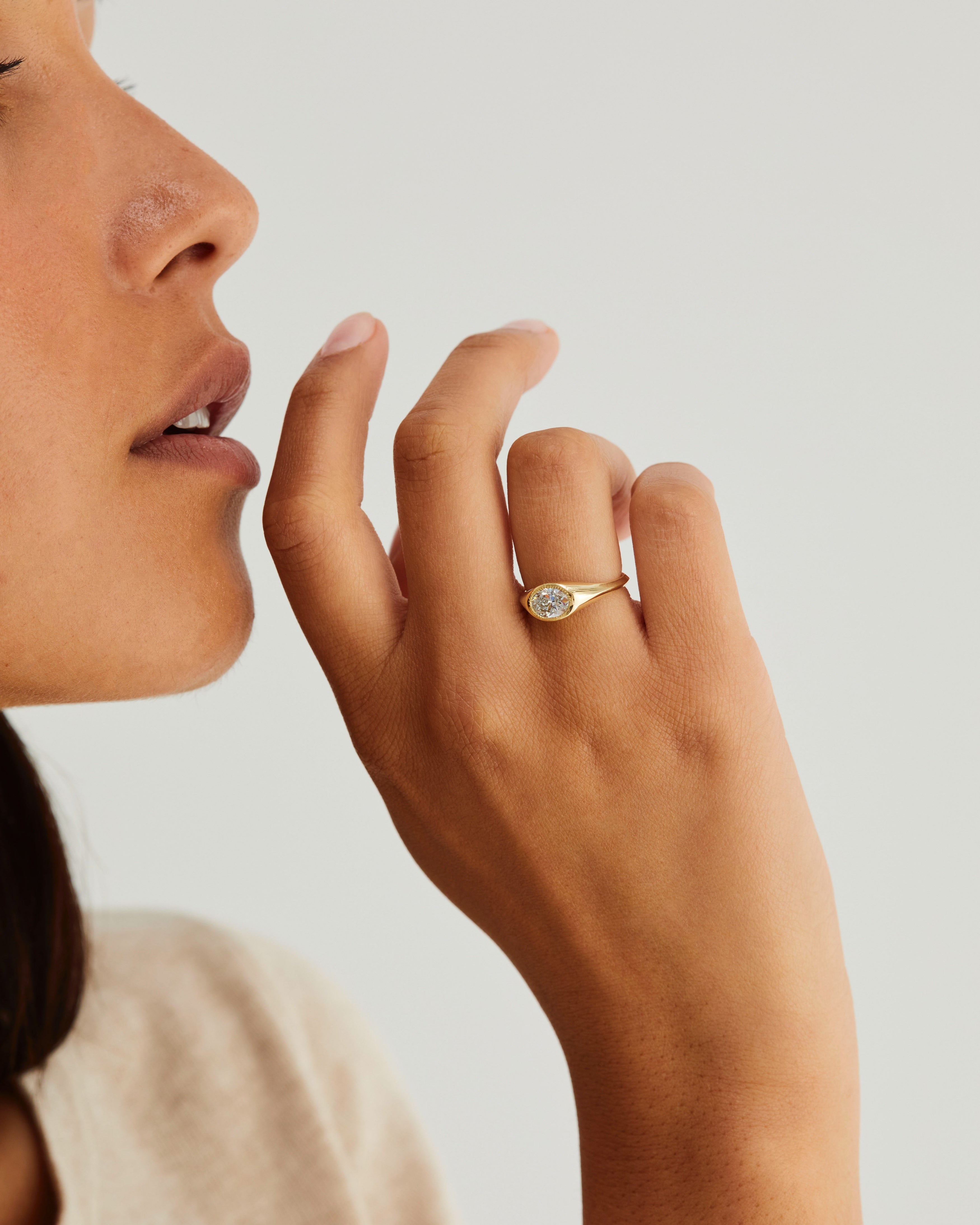 A women wears a polished Atlas Signet with an oval white diamond, in yellow gold