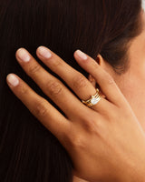 A woman wears the Belle Ring, stacked with a double cascade diamond band and the diamond mandala solitaire, in yellow gold