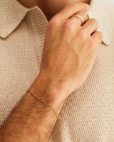 A male wears the Anam Charm Bracelet in Yellow Gold