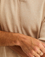 A male wears the fine Figaro chain bracelet in yellow gold