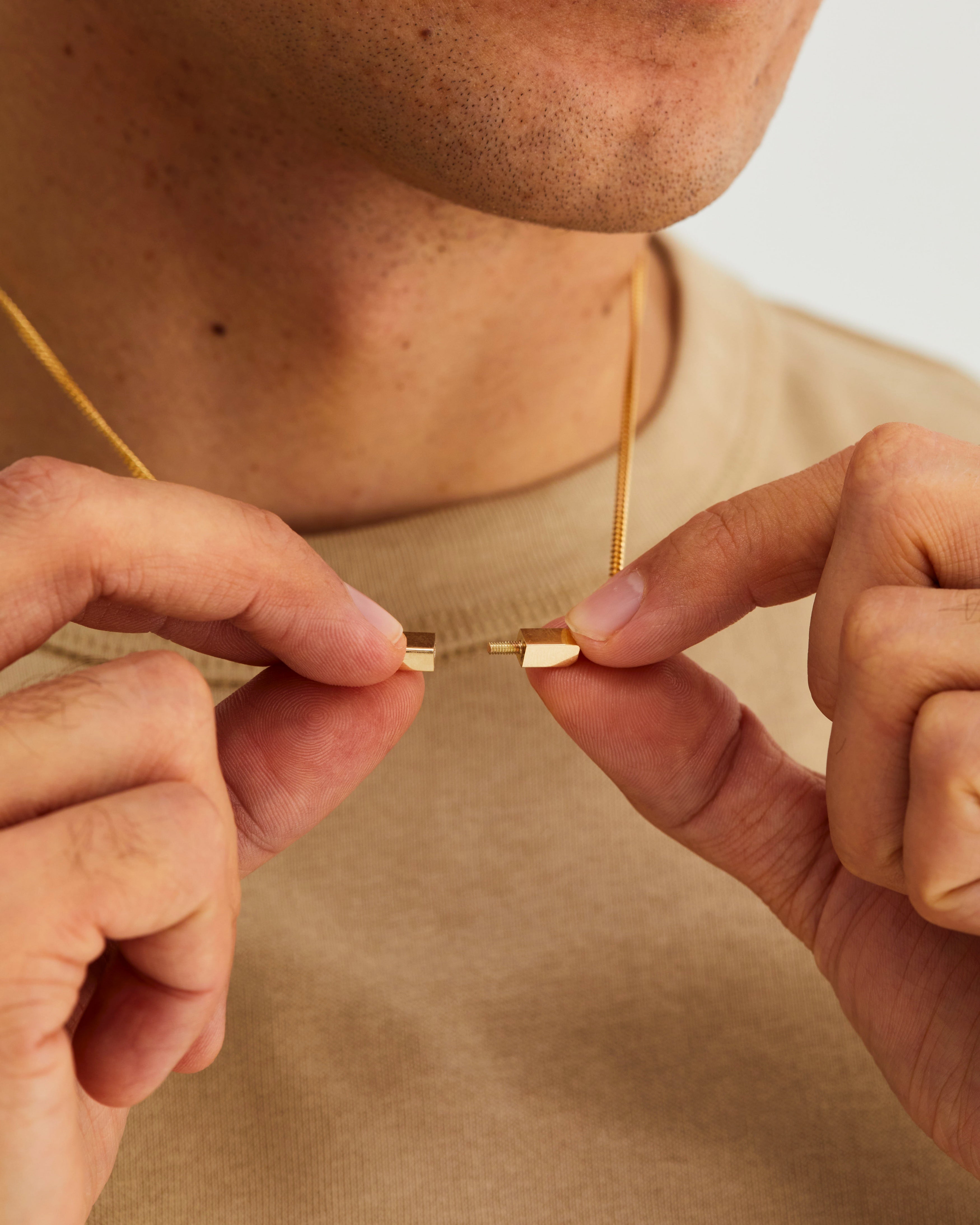 A man showcasing the clasp of the Guardian Chain, in yellow gold.