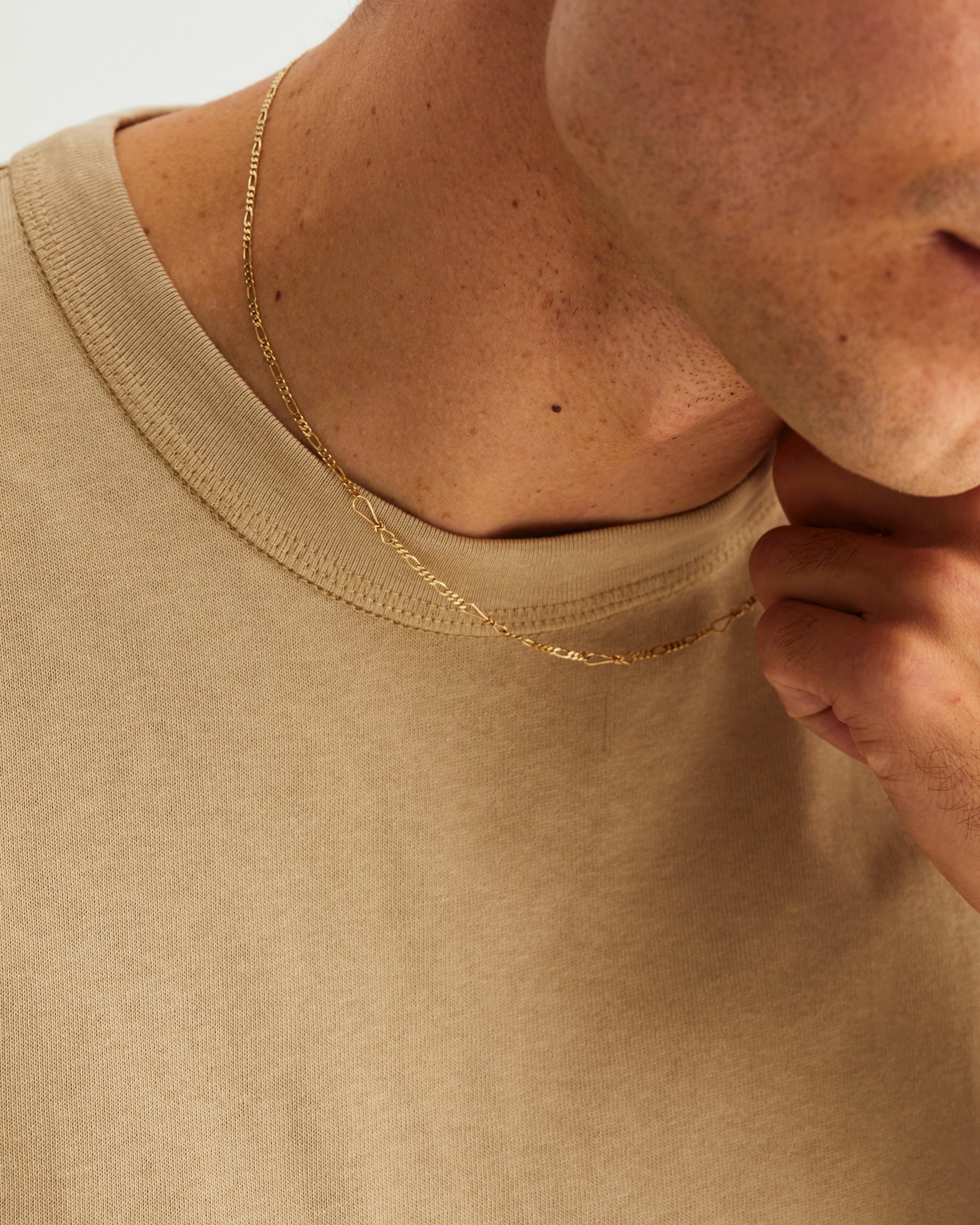 A man wears the Anam Charm Necklace in Yellow Gold