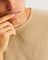 A man wears the simple chain necklace in yellow gold