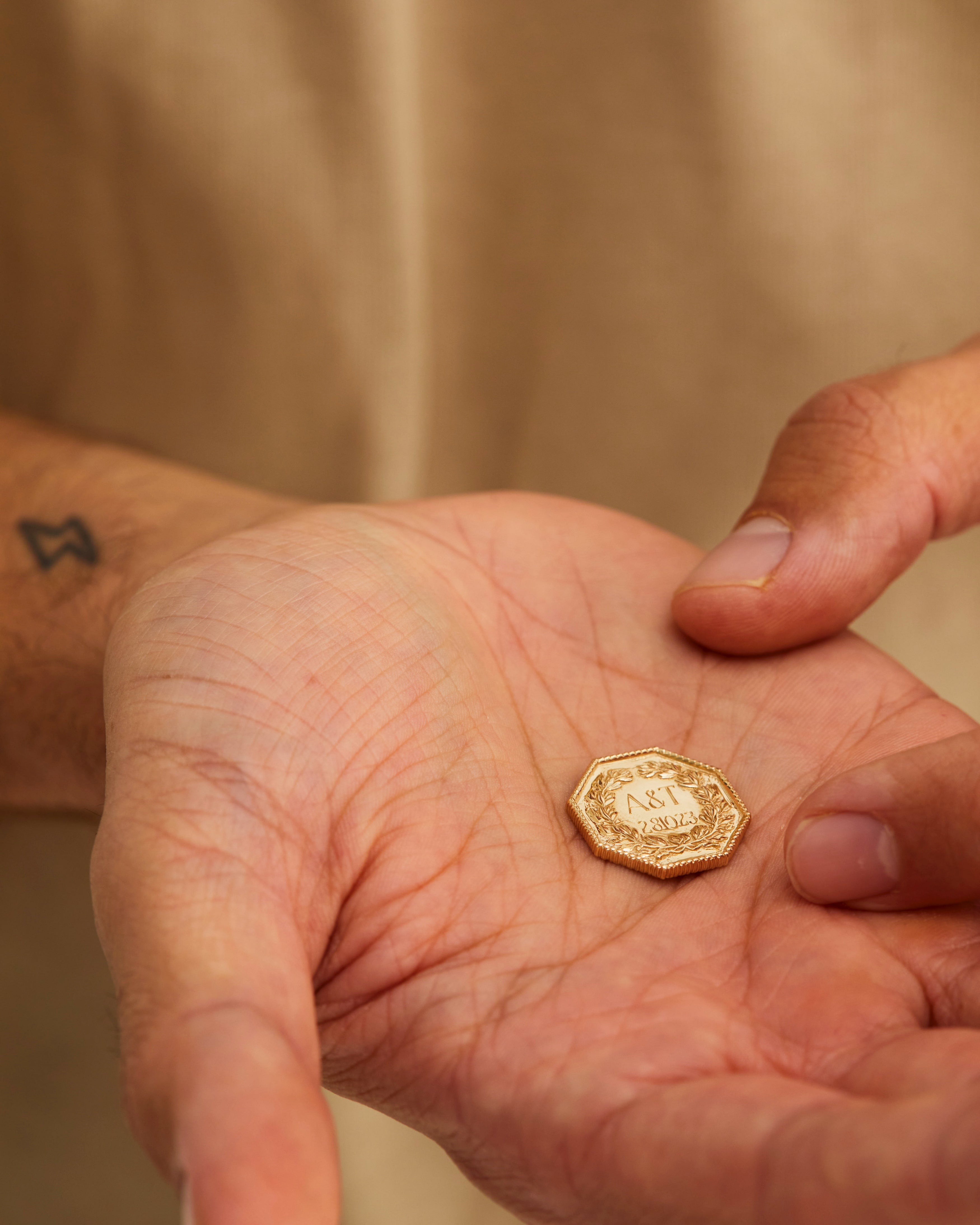 A man holding the Aeneid Wedding Coin in his palm