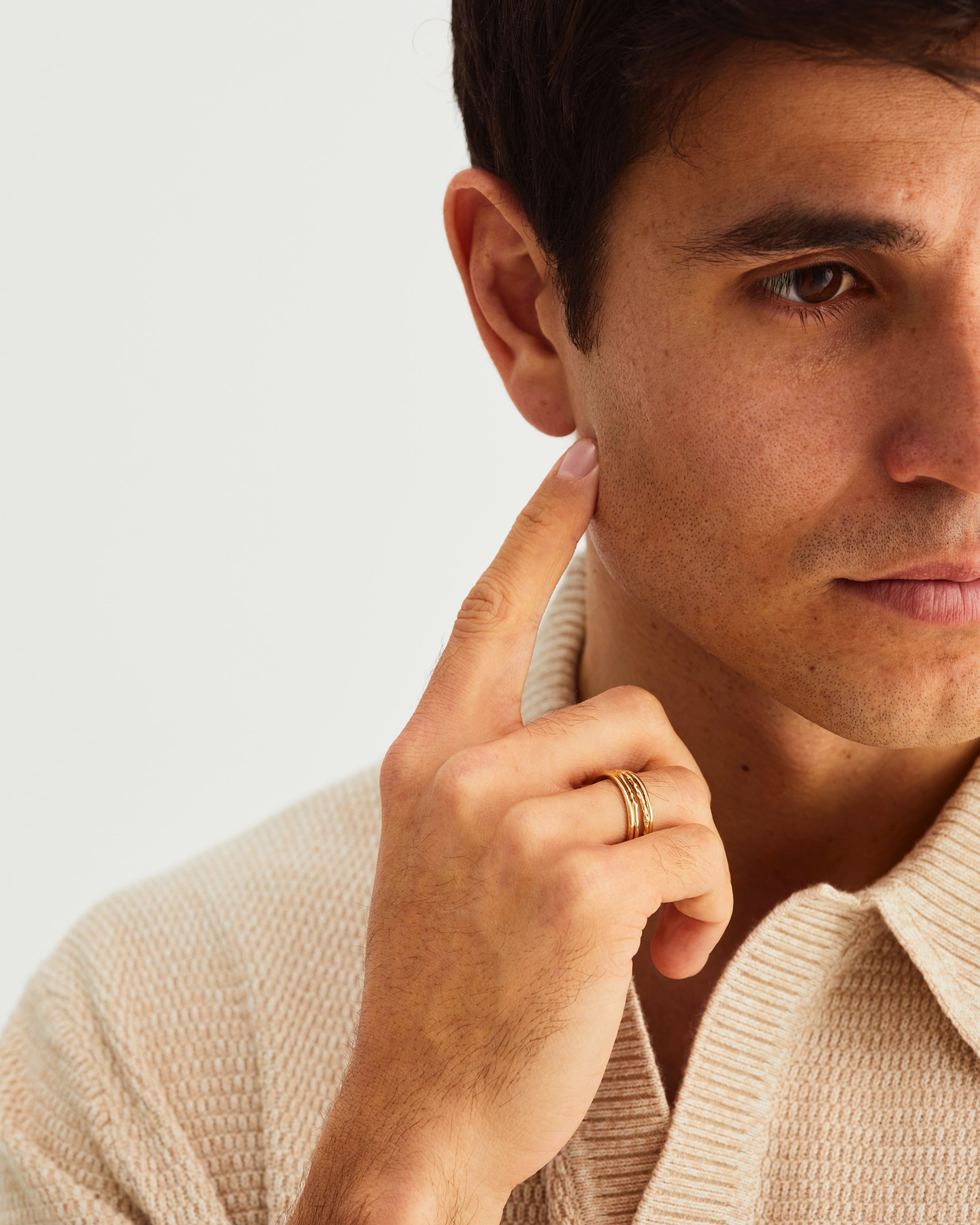A man wears the fine faceted stacking rings and fine stacking rings in yellow gold