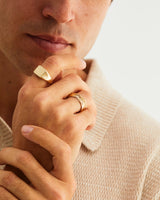 A man wears the sempre signet and Kamali ring in yellow gold