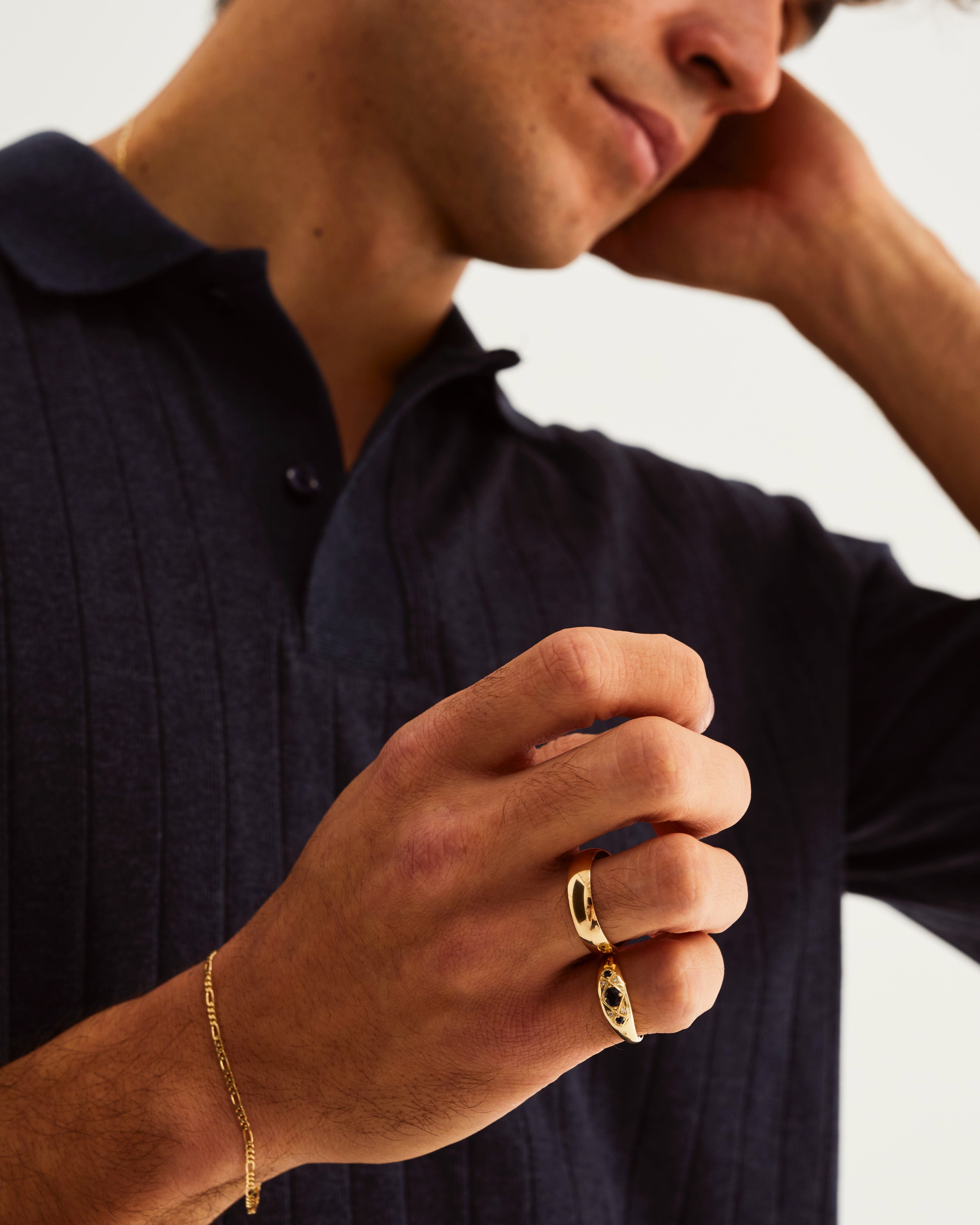 A man wears the Seule Cheri ring with dark blue sapphires, and a half round wedding ring in yellow gold
