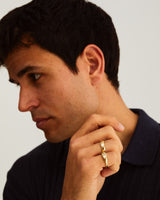 A man wears the Seule Single Ring with Diamond, and a half round bold wedding ring in. yellow gold