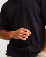 A man wears an Amos Ring with dark blue sapphires in yellow gold