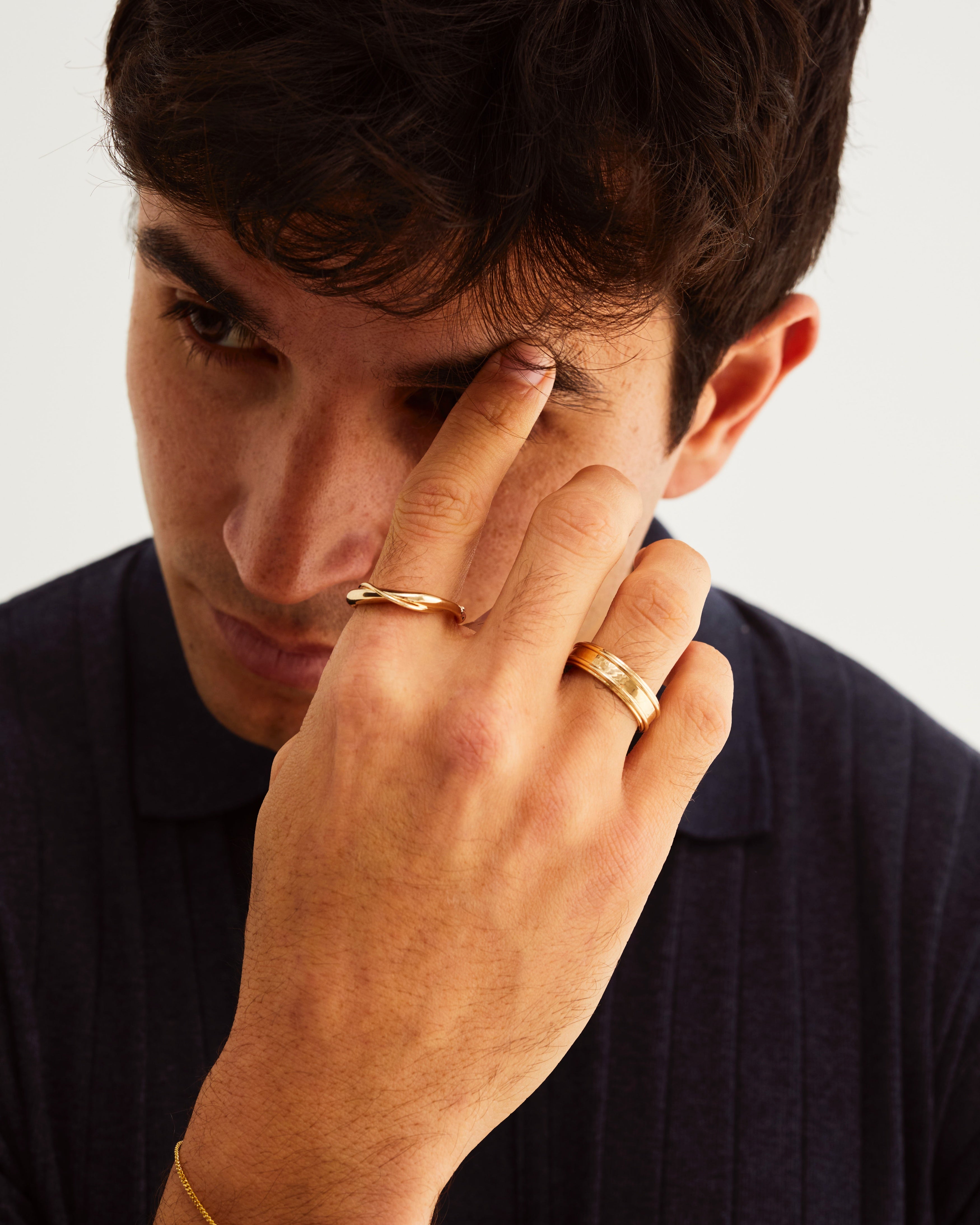 A man wears the 6mm border wedding ring and Dali ring in yellow gold
