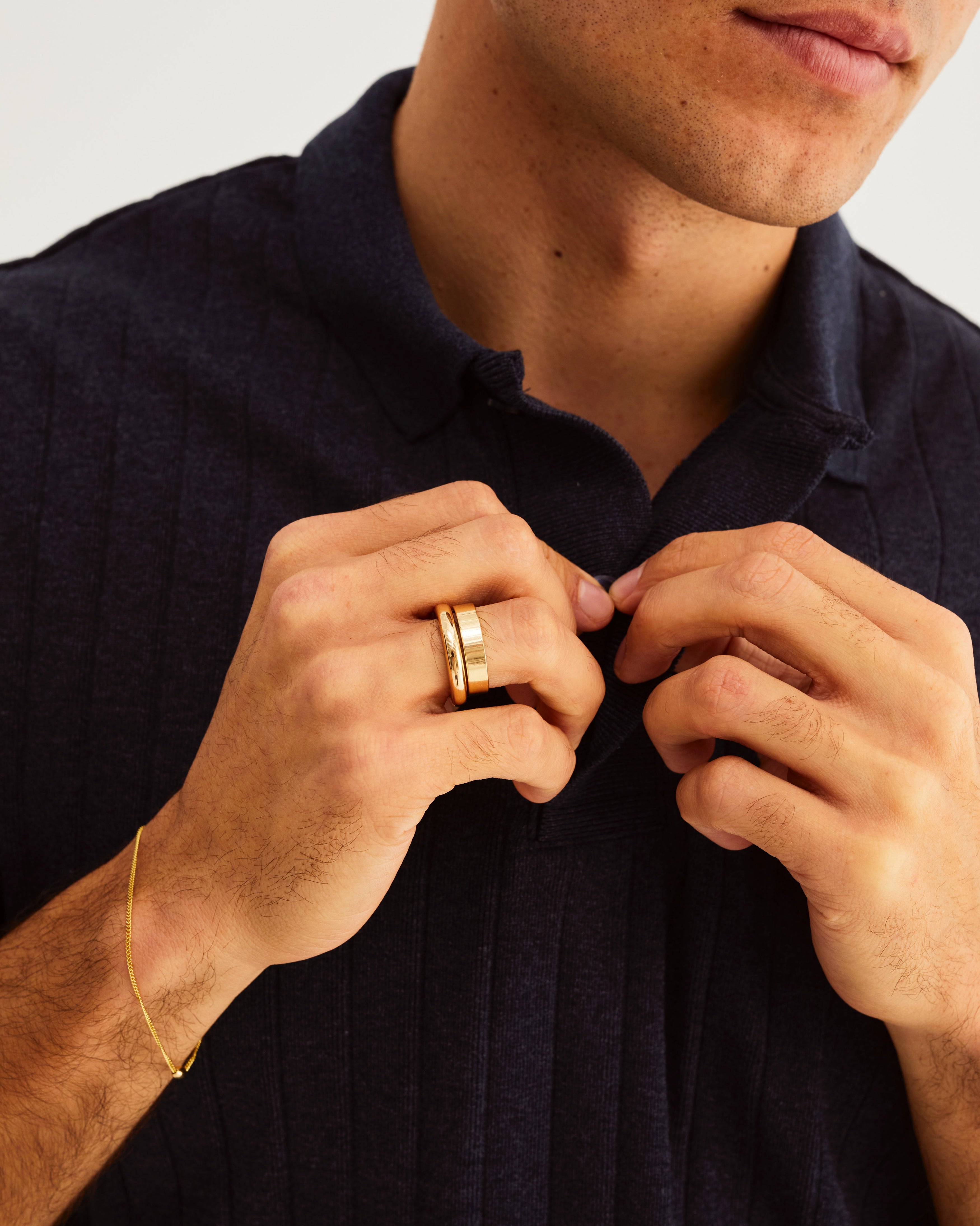 A man wears a 4mm bold curve ring stacked with a 4mm flat wedding band in yellow gold