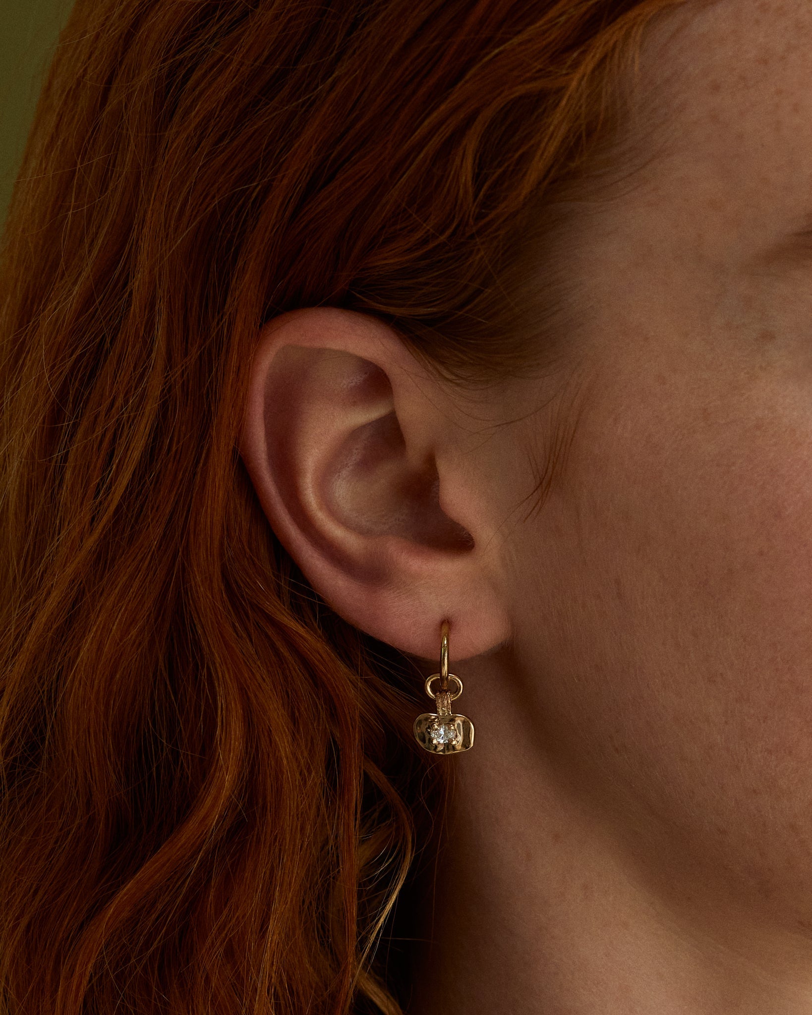 A close up on an ear showcasing the Terra Hoop | Diamond in yellow gold.