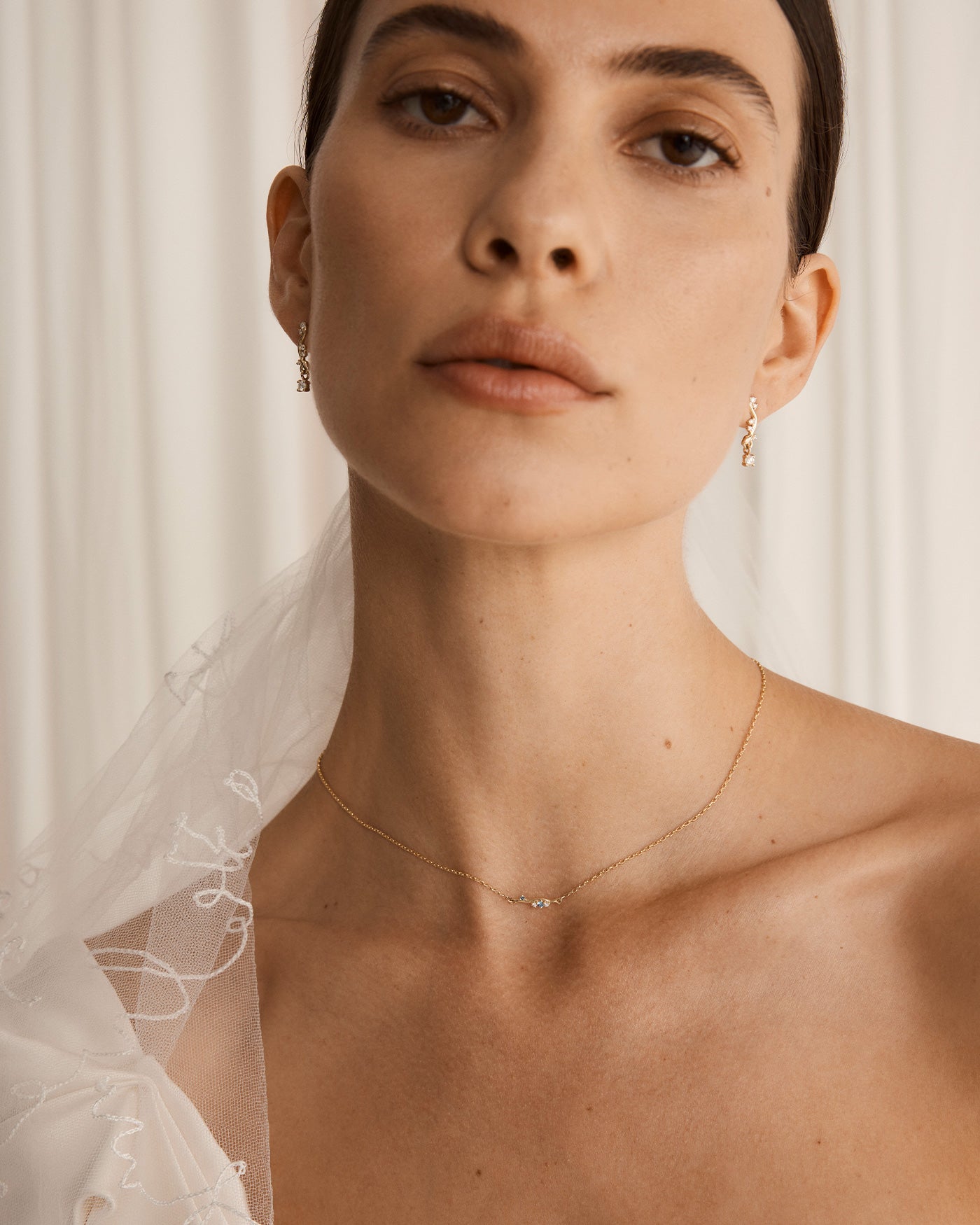 Image of woman wearing a bridal gown and wearing the ember charm necklace with blue sapphires and white diamonds