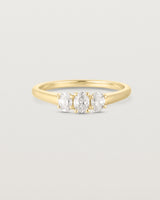 Front on deep etched image of a yellow gold engagement ring with three oval laboratory grown diamonds.
