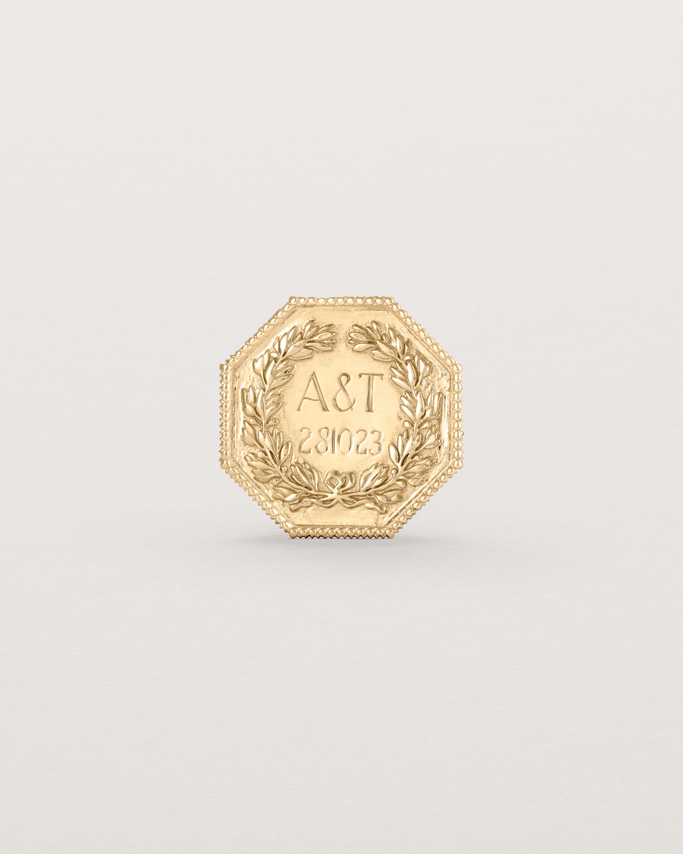 yellow gold six pence coin engraved with a crest and initials