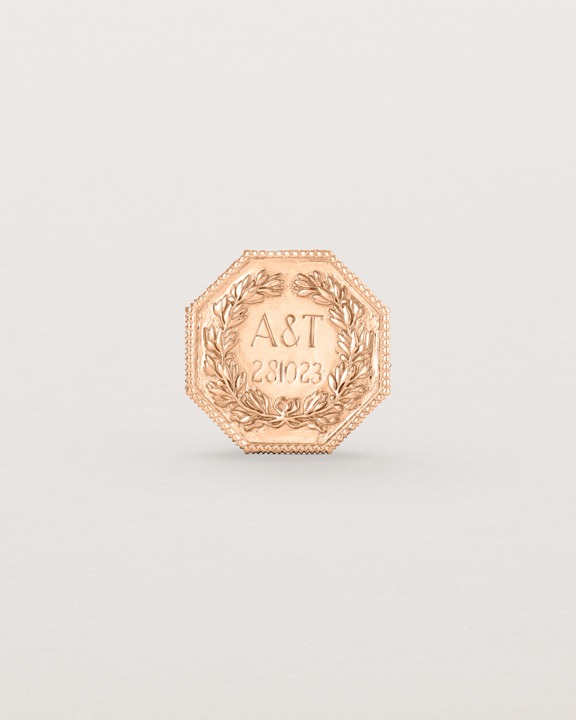 Rose gold six pence coin engraved with a crest and initials
