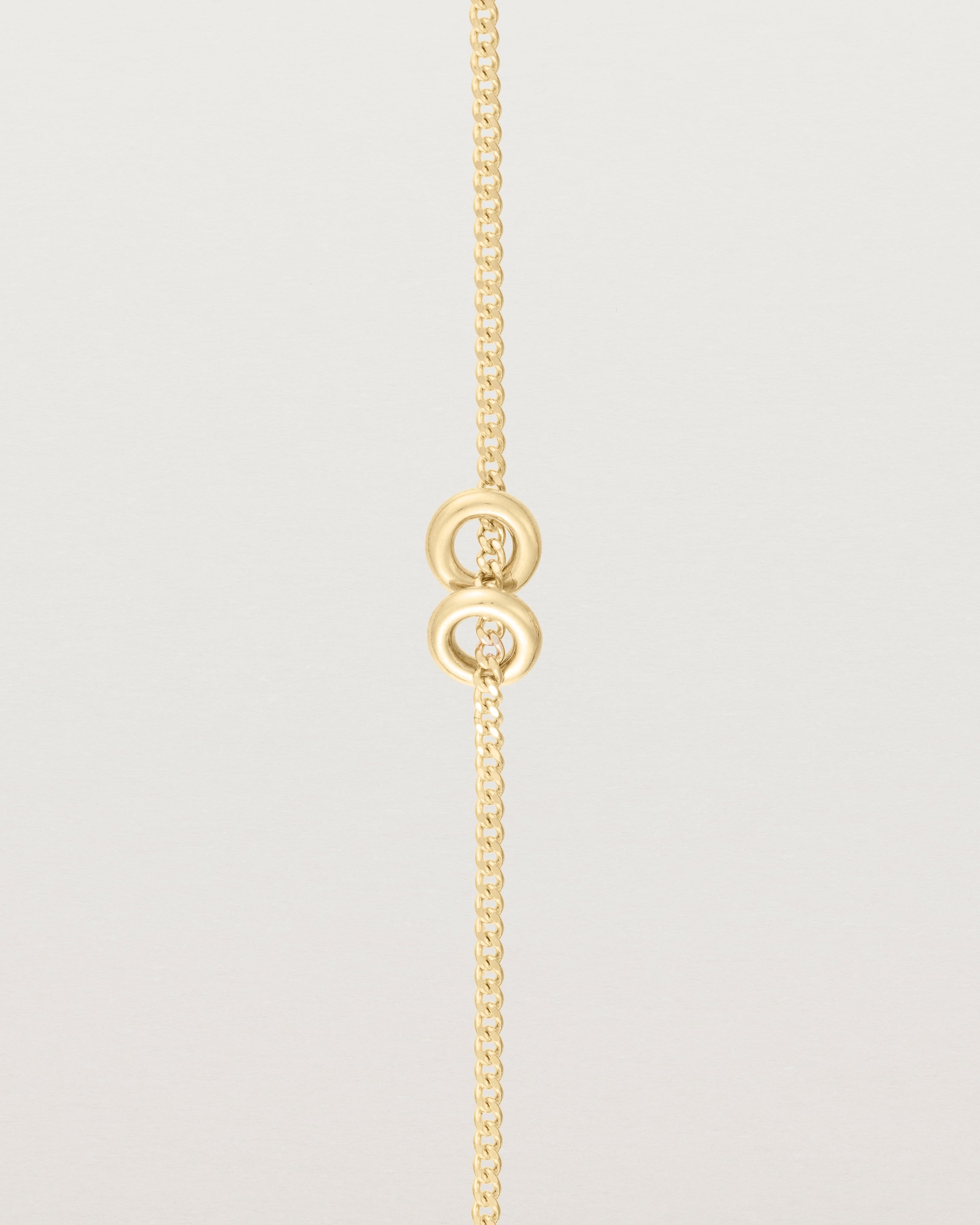 close up view of Aether bracelet featuring two round charms in yellow gold