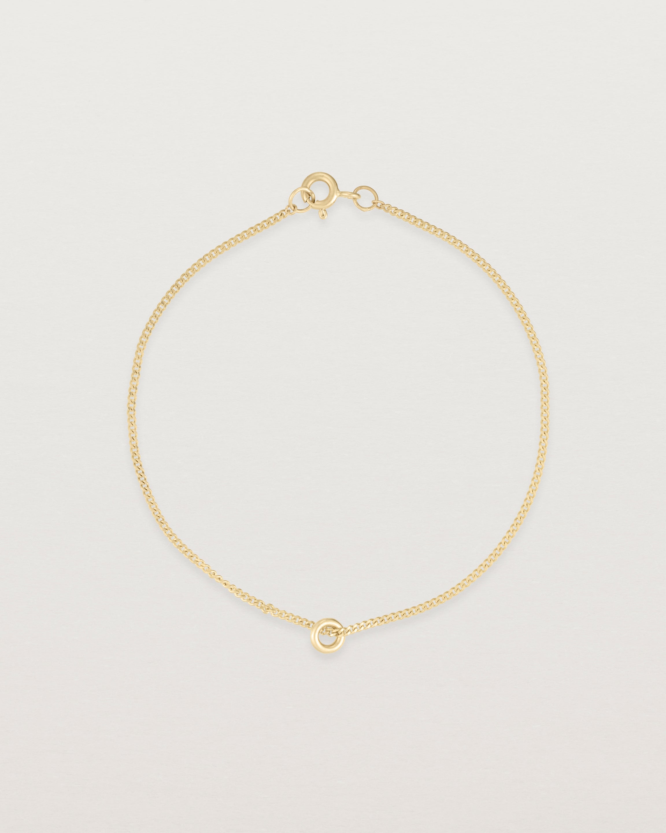 Top view of Aether bracelet featuring one round charm in yellow gold