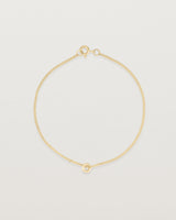 Top view of Aether bracelet featuring one round charm in yellow gold