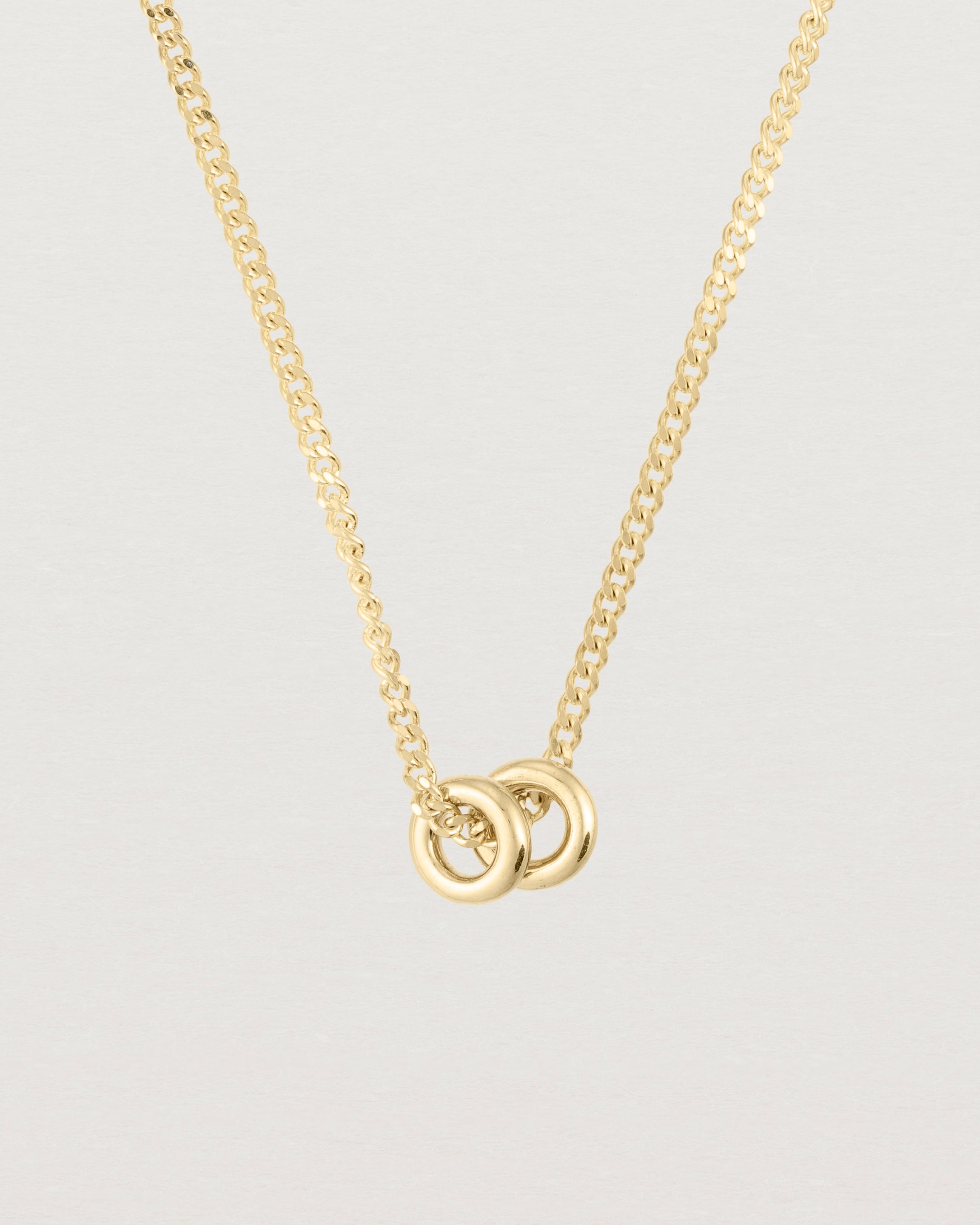 close up of Aether necklace showing two round charms in yellow gold
