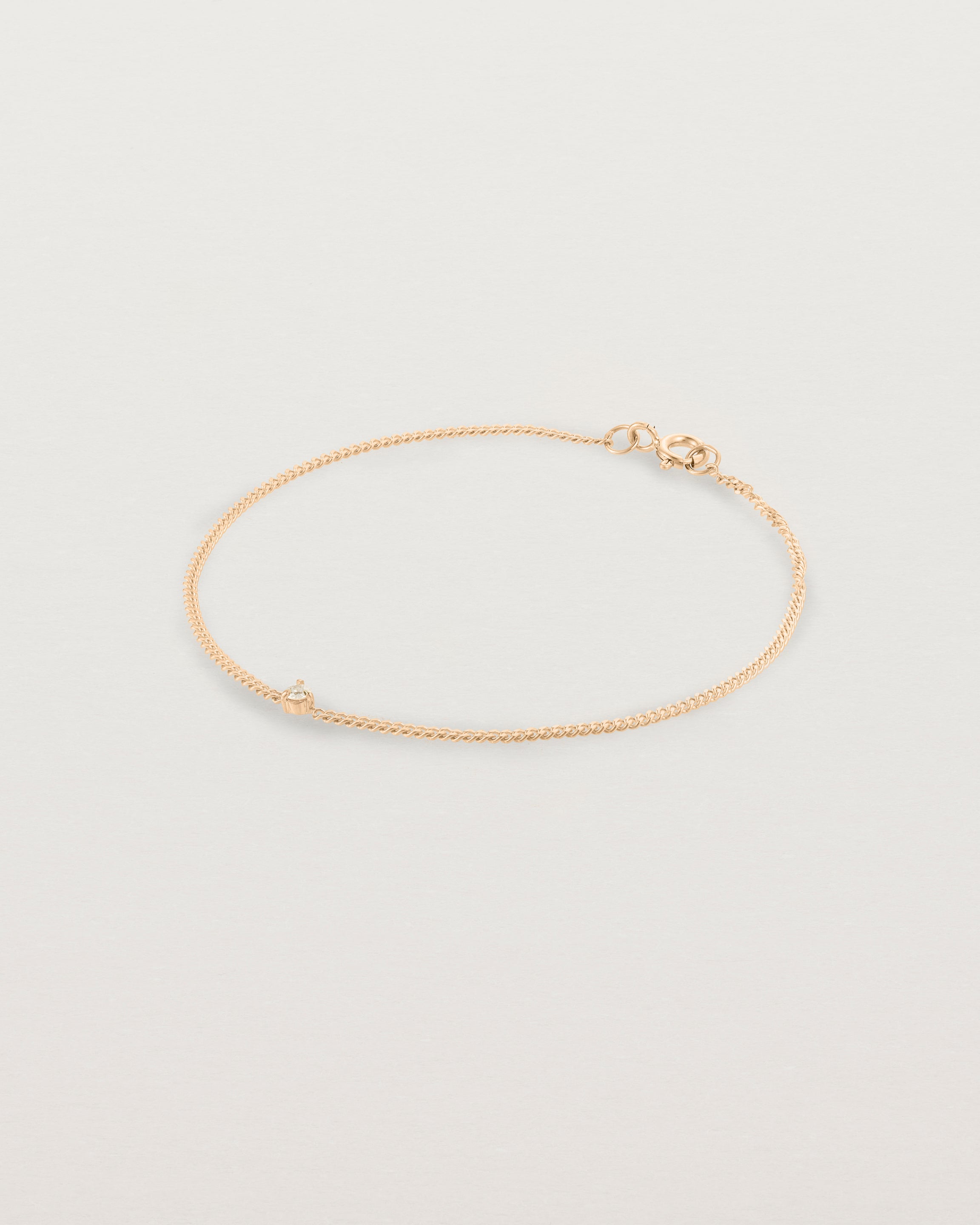 A rose gold chain bracelet featuring a single white old cut diamond