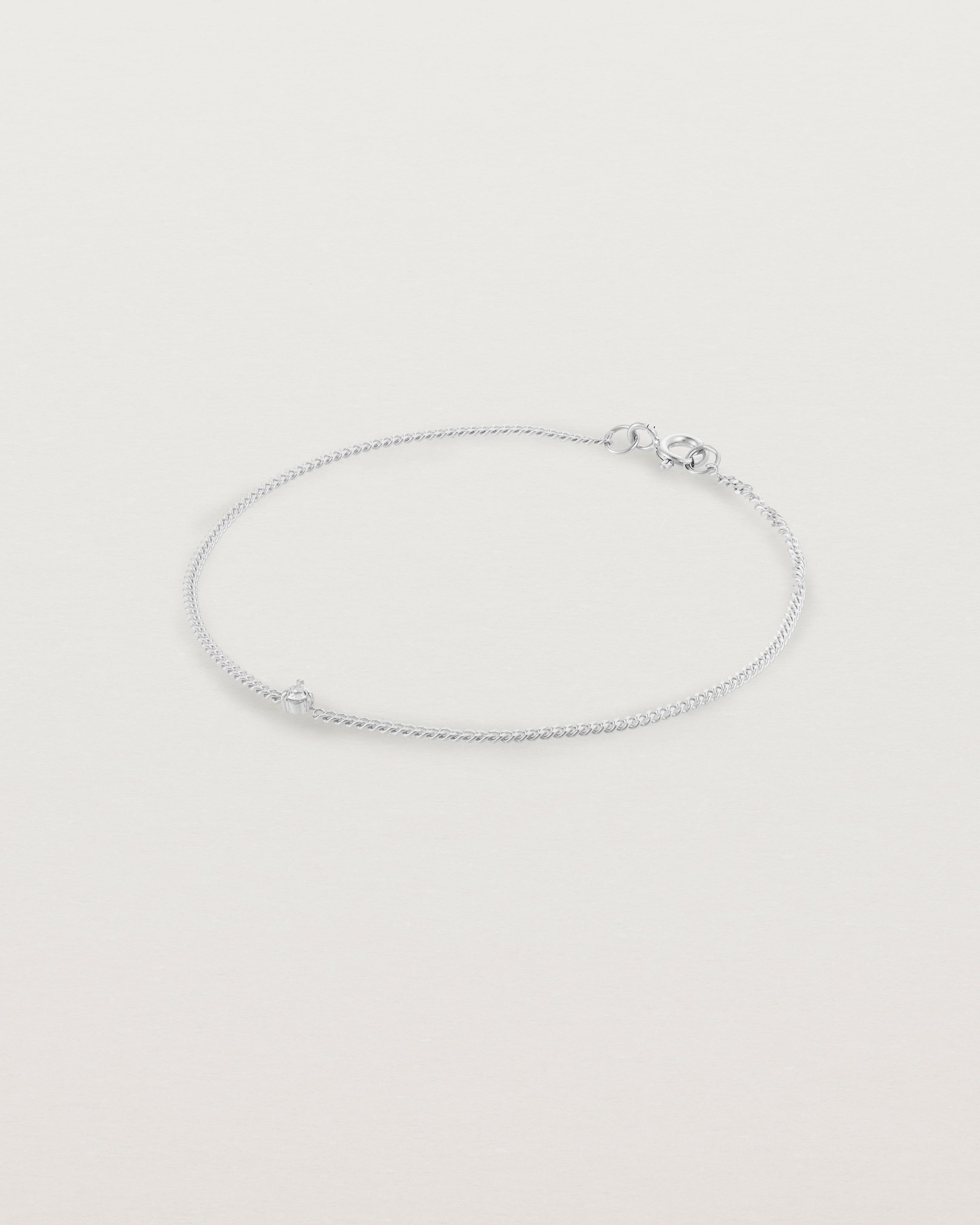 A white gold chain bracelet featuring a single white old cut diamond