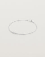 A white gold chain bracelet featuring a single white old cut diamond