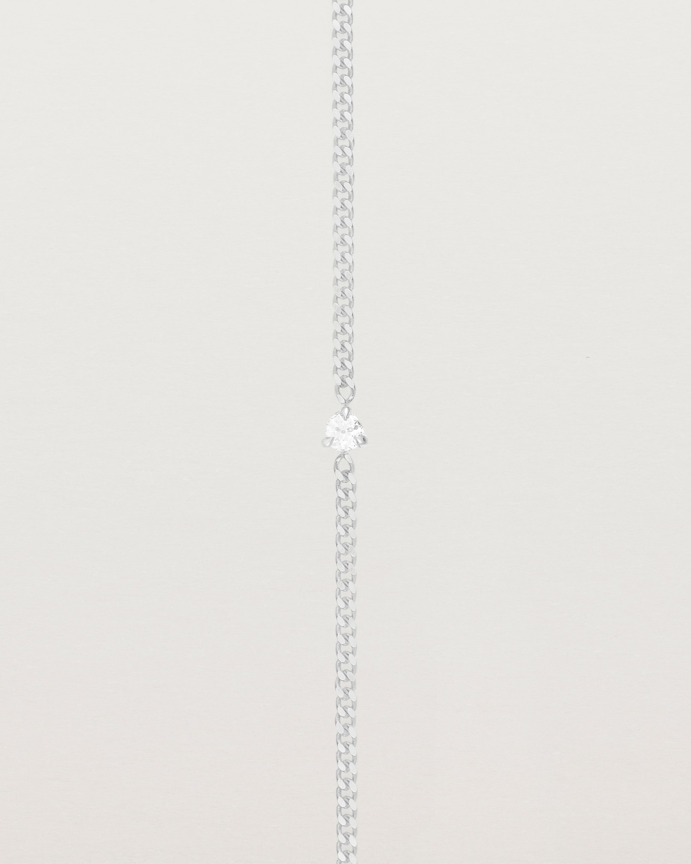 A white gold chain bracelet featuring a single white old cut diamond