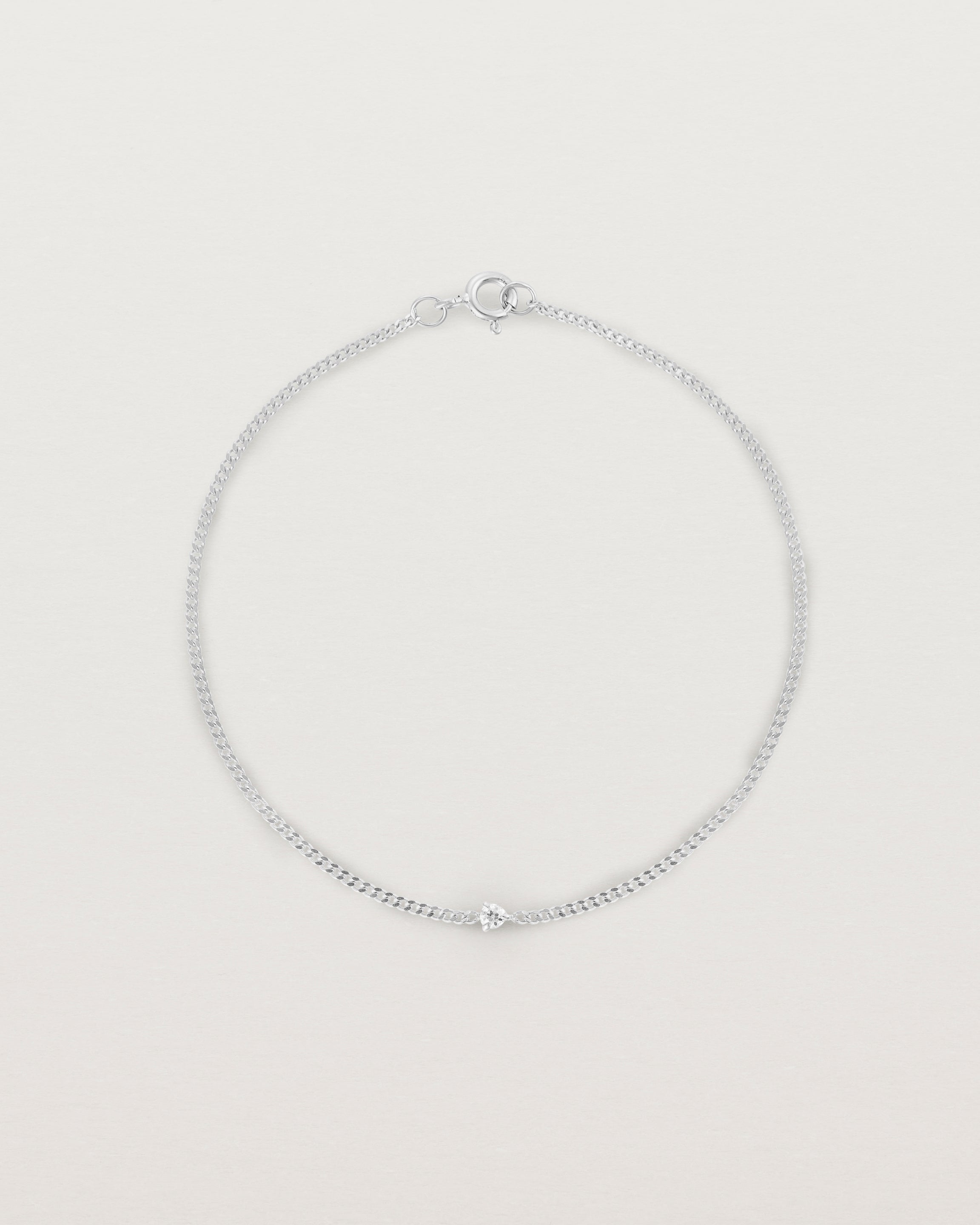 A white gold chain bracelet featuring a single white old cut diamond