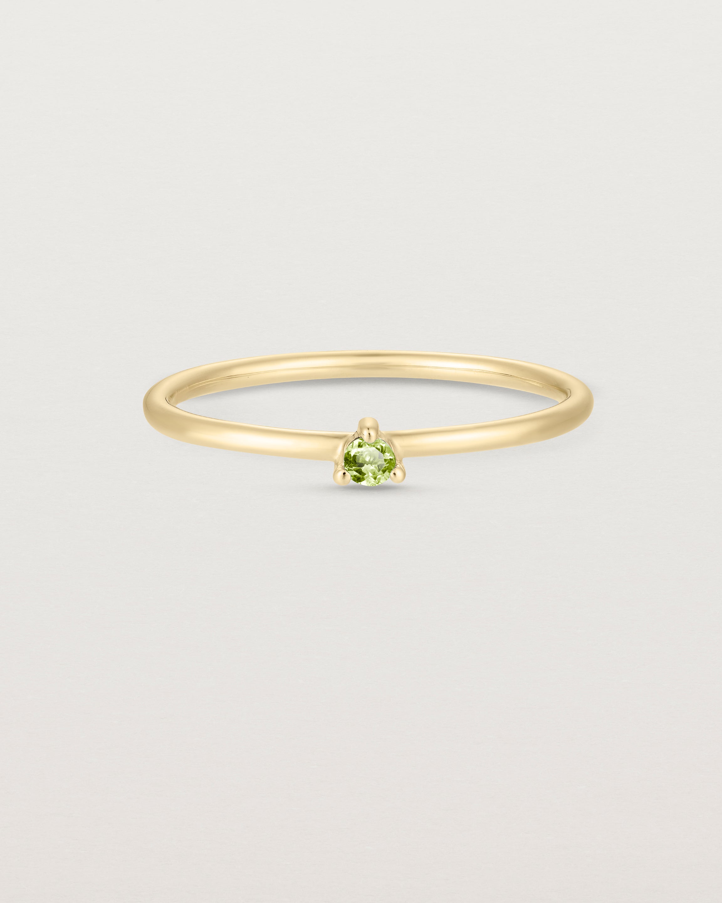 Front facing deep etched image of a yellow gold ring with a peridot birthstone.