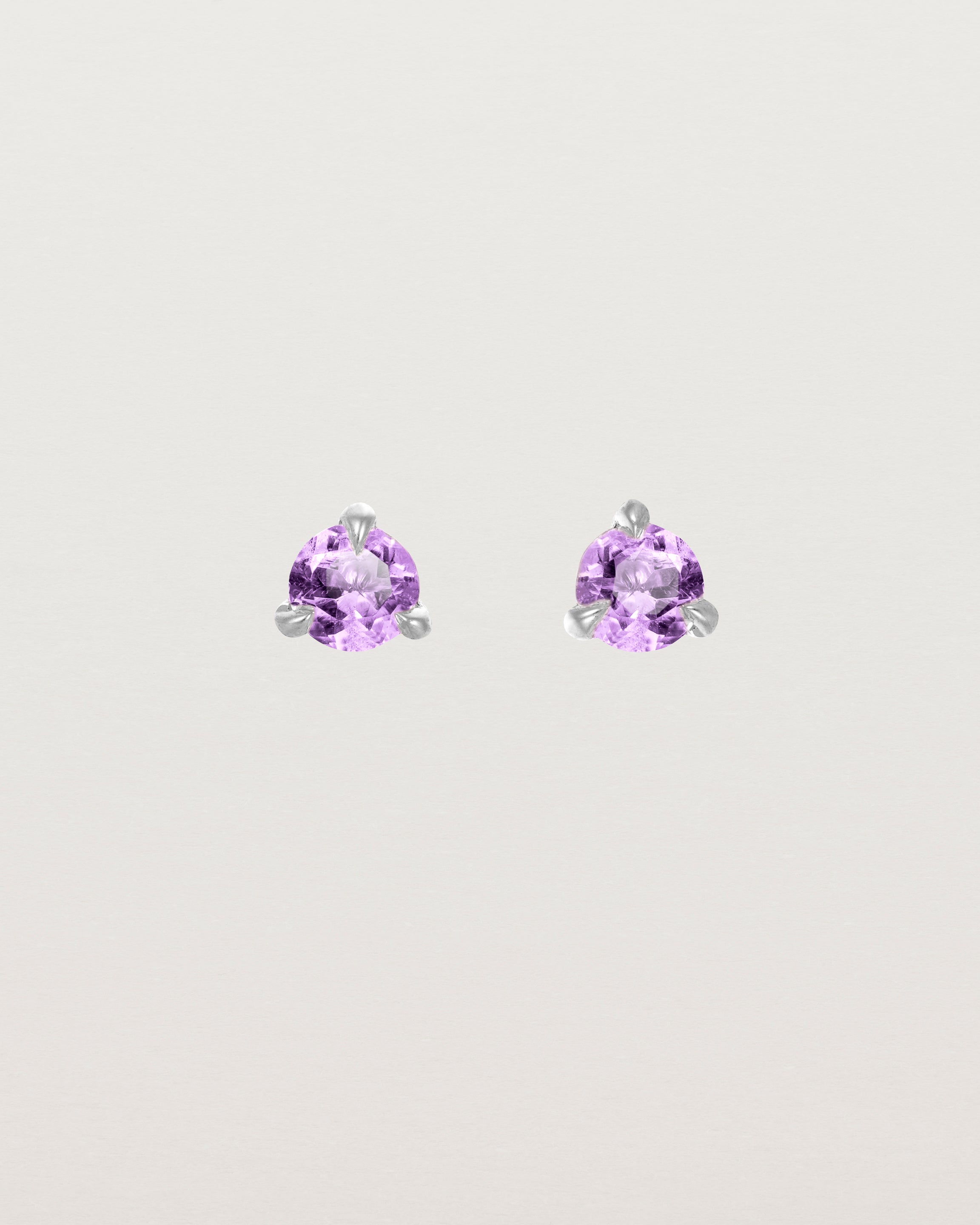 Front facing deep etched image of a pair of white gold earrings with an amethyst birthstone.