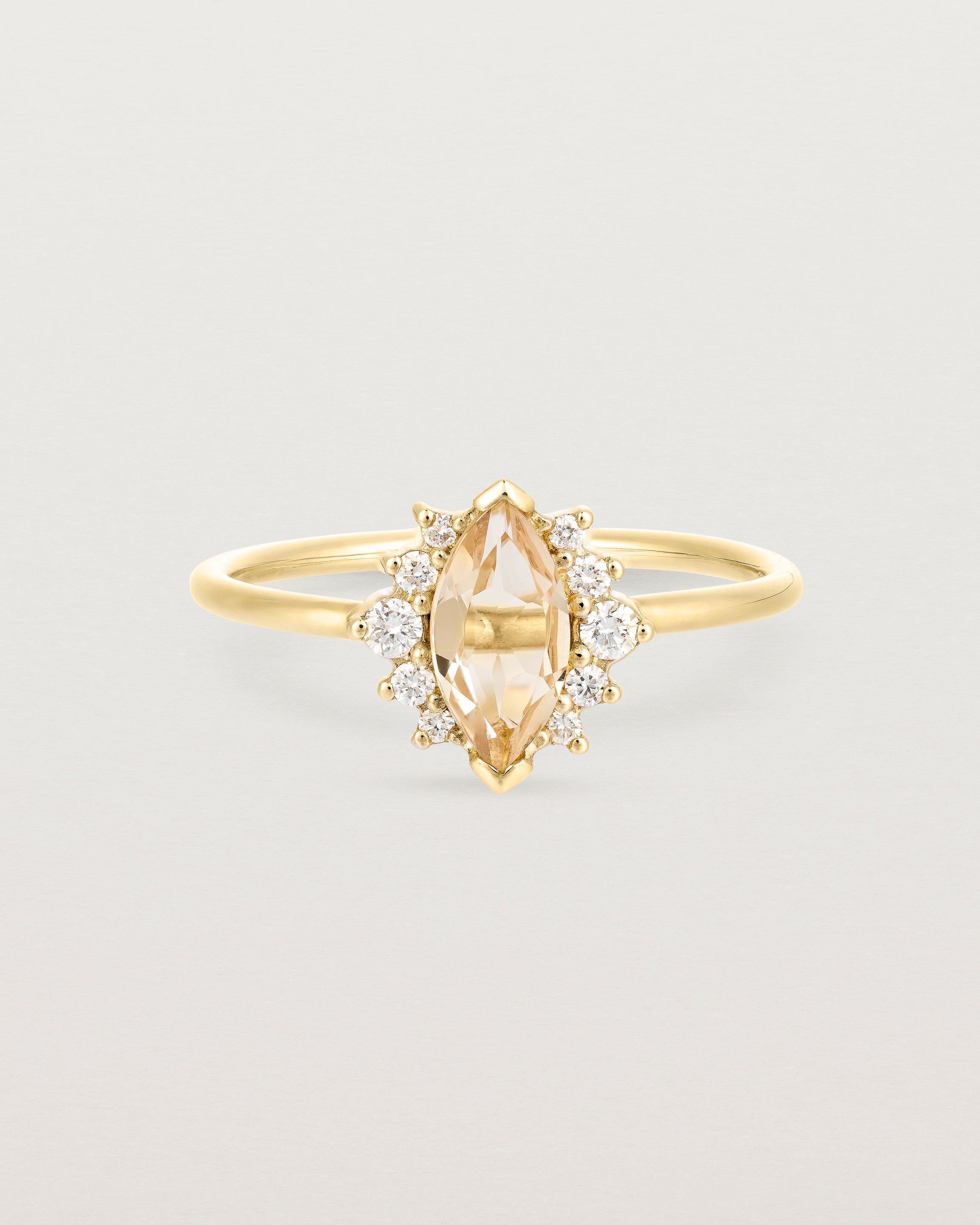 A yellow gold ring featuring a marquise champagne quartz with a halo of white diamonds