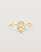 A yellow gold ring featuring a marquise champagne quartz with a halo of white diamonds