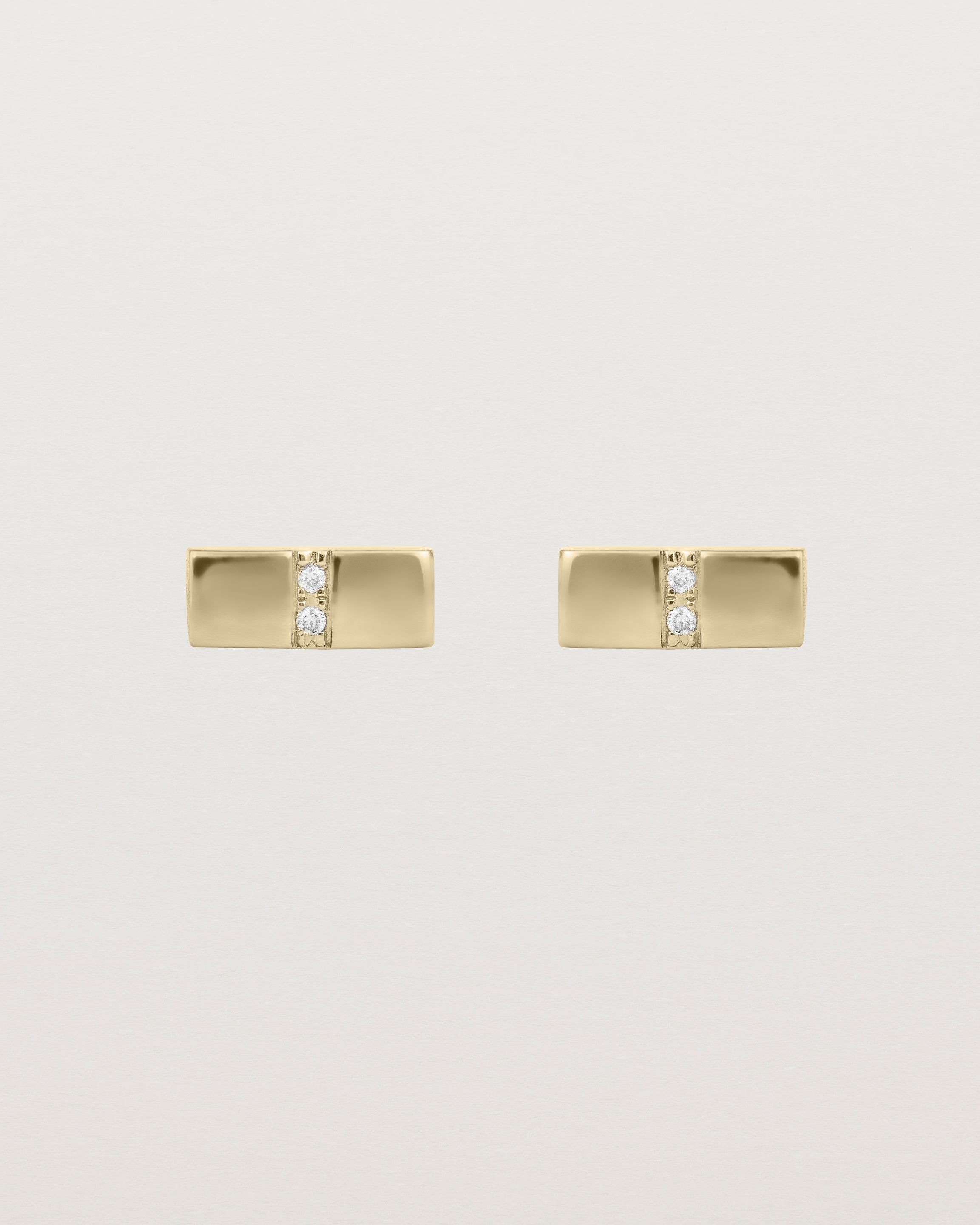A pair of small yellow gold rectangle studs featuring two white diamonds set in the centre