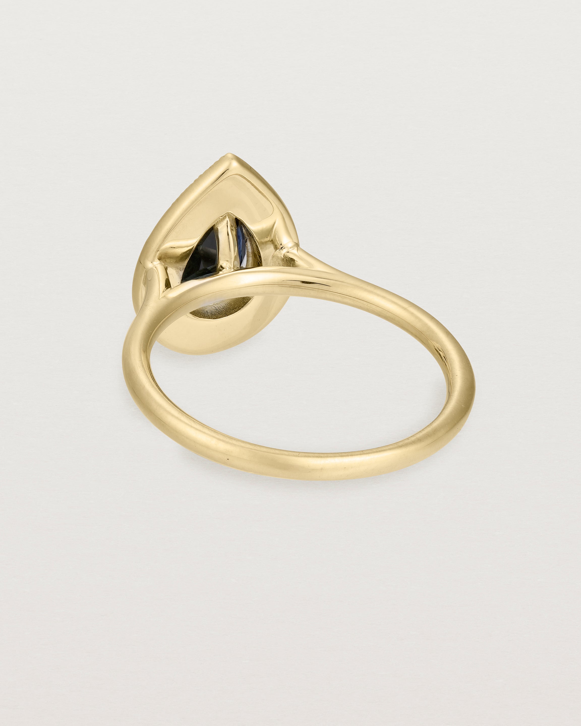 back view pear halo ring featuring a pear cut australian blue sapphire and a halo of white diamonds in yellow gold