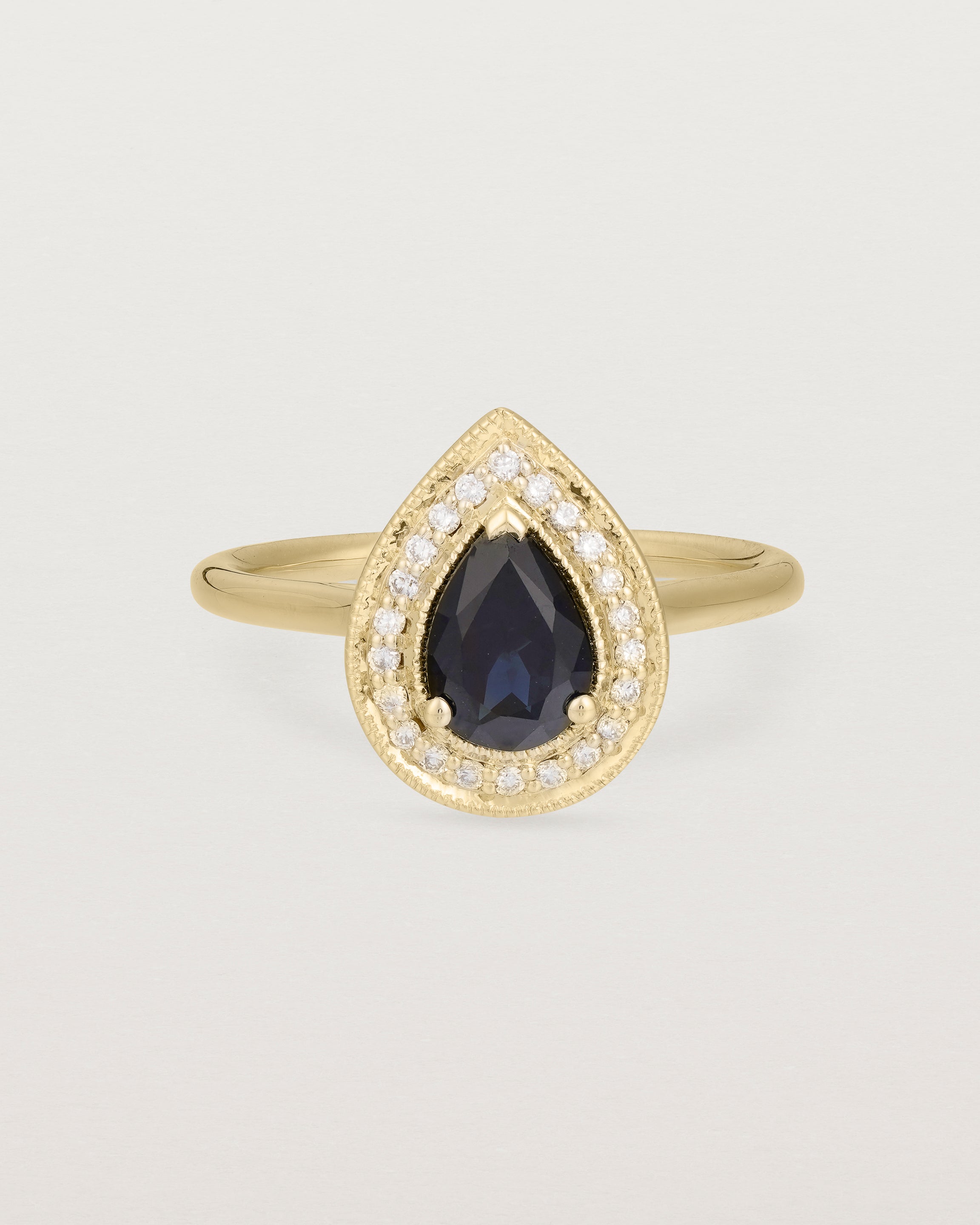 Front view pear halo ring featuring a pear cut australian blue sapphire and a halo of white diamonds in yellow gold