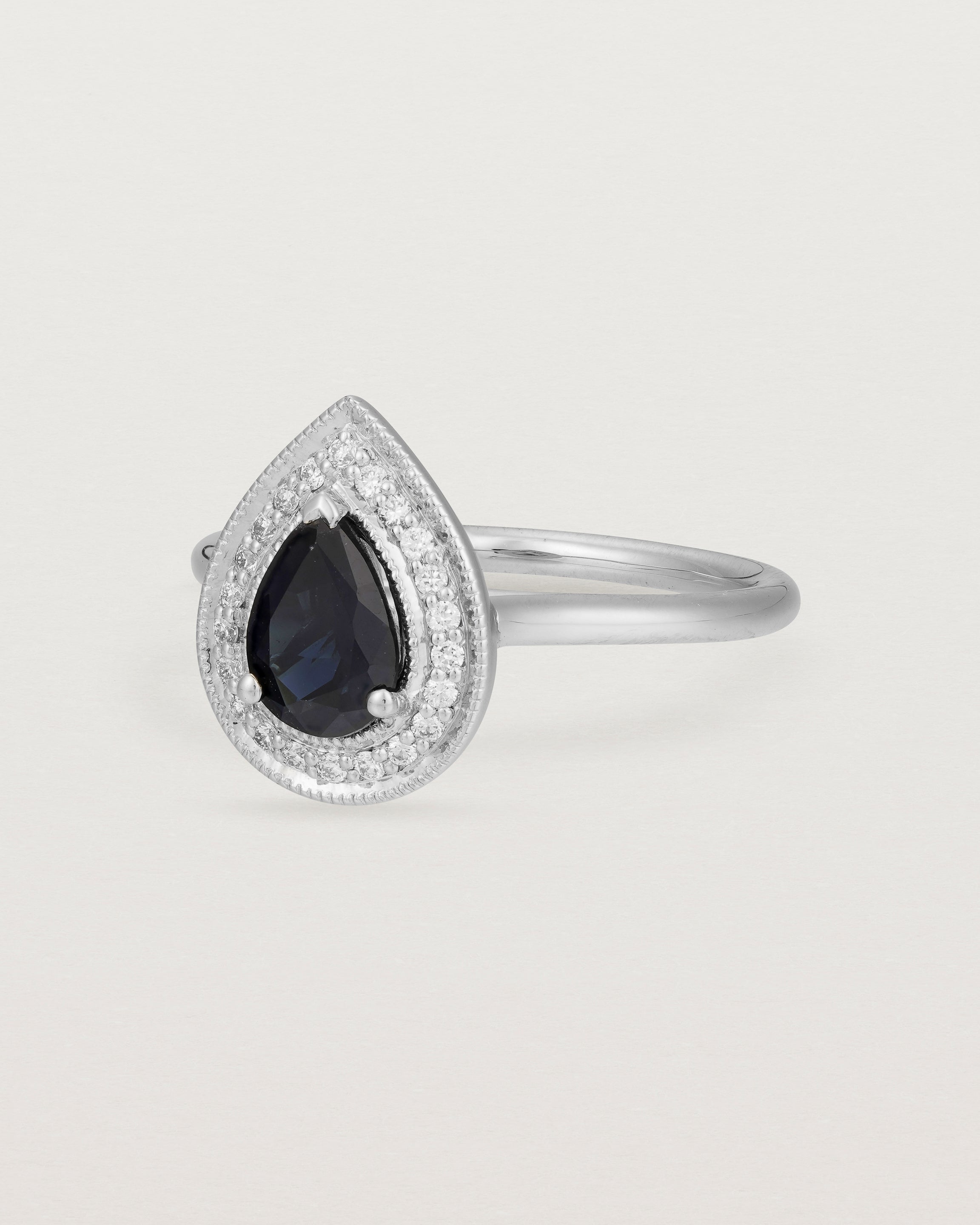 front view pear halo ring featuring a pear cut australian blue sapphire and a halo of white diamonds in white gold