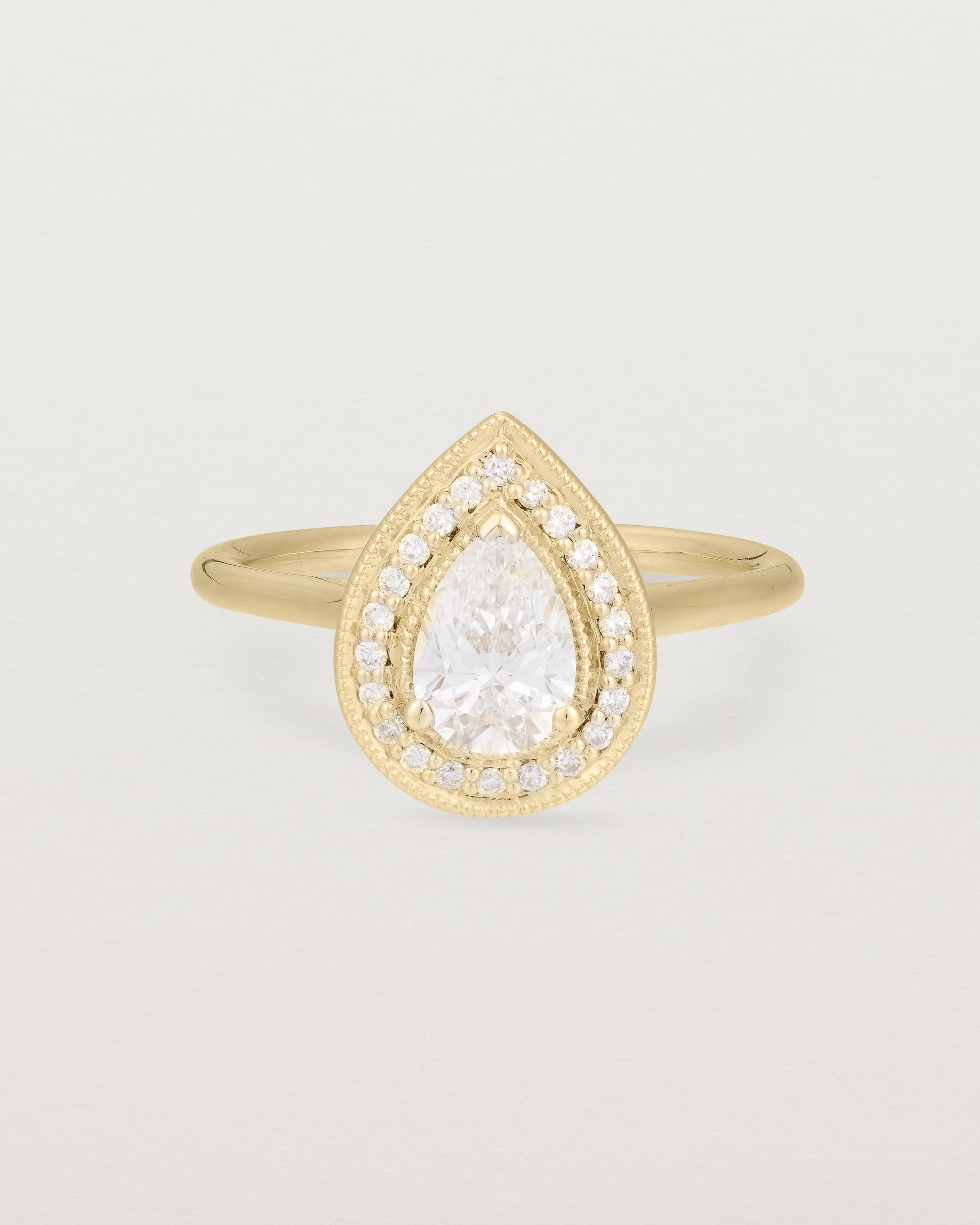 Front view pear halo ring featuring a pear cut clear laboratory grown diamond and a halo of white diamonds in yellow gold