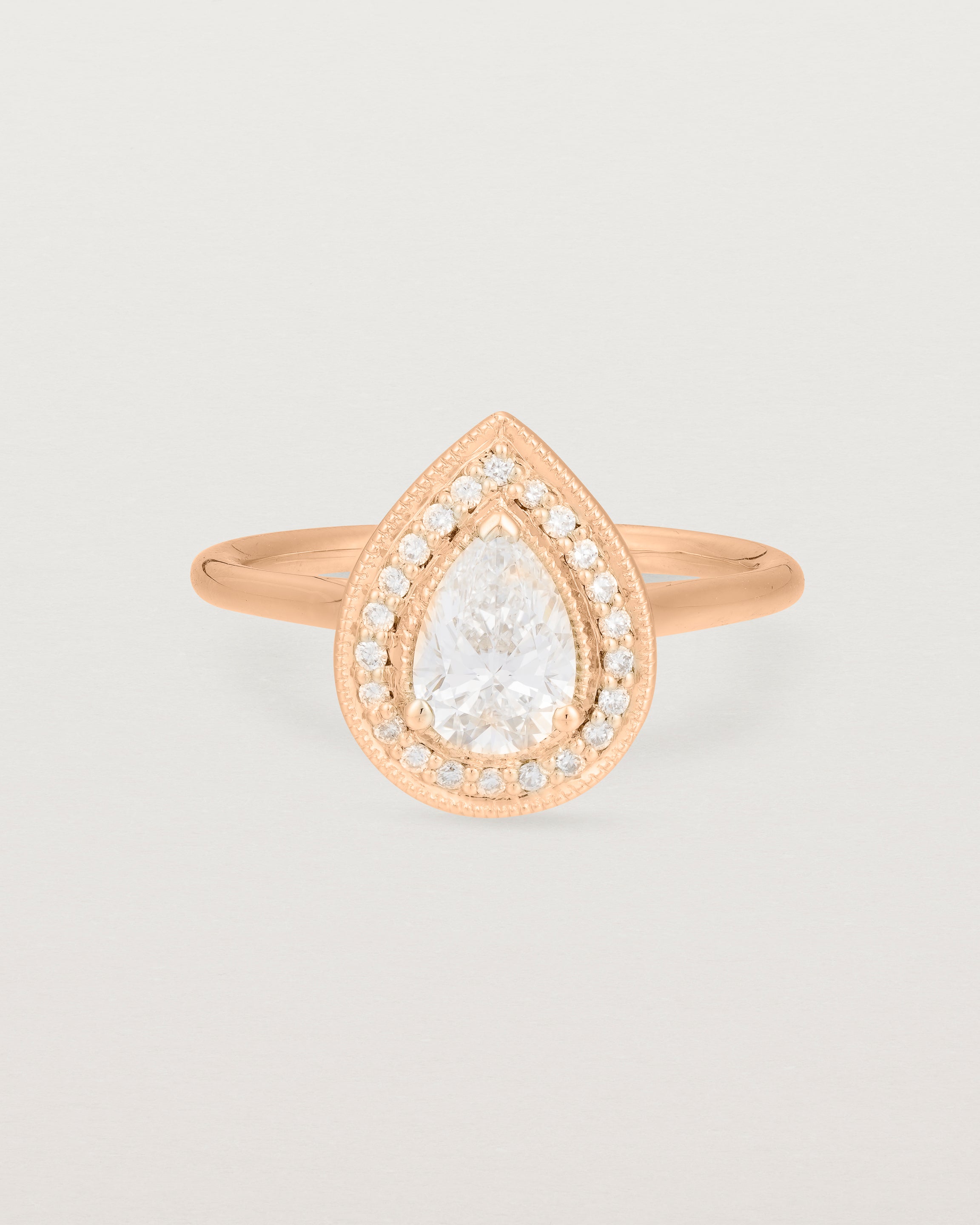 Side view pear halo ring featuring a pear cut clear laboratory grown diamond and a halo of white diamonds in rose gold